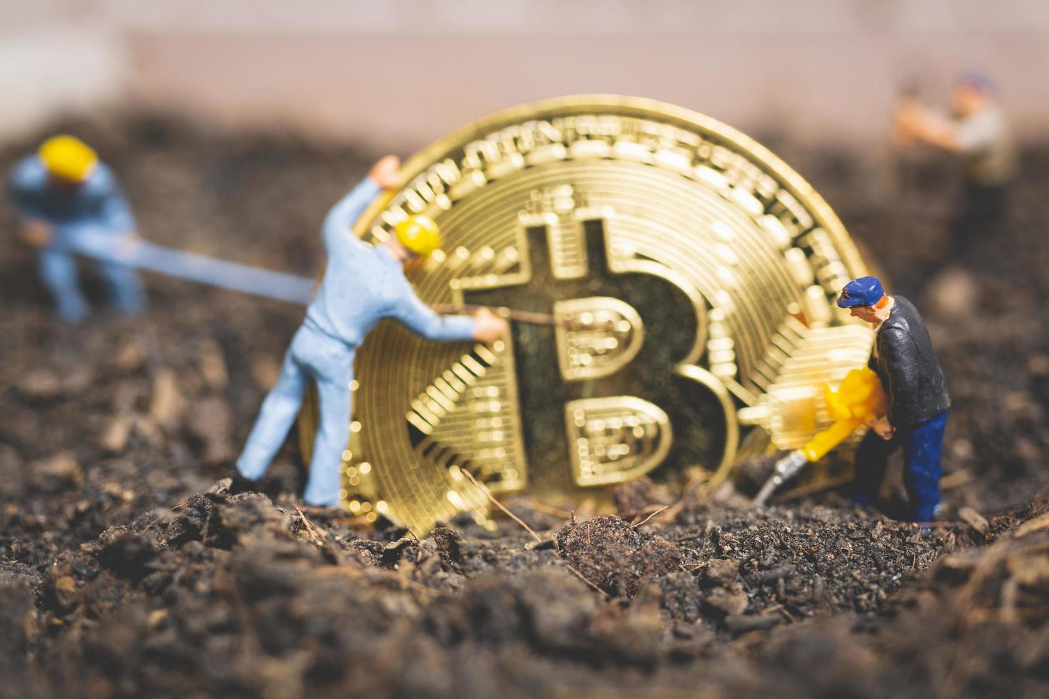 lavoratori in miniatura che scavano il terreno per scoprire lucida criptovaluta bitcoin, concetto di lavoro di successo foto