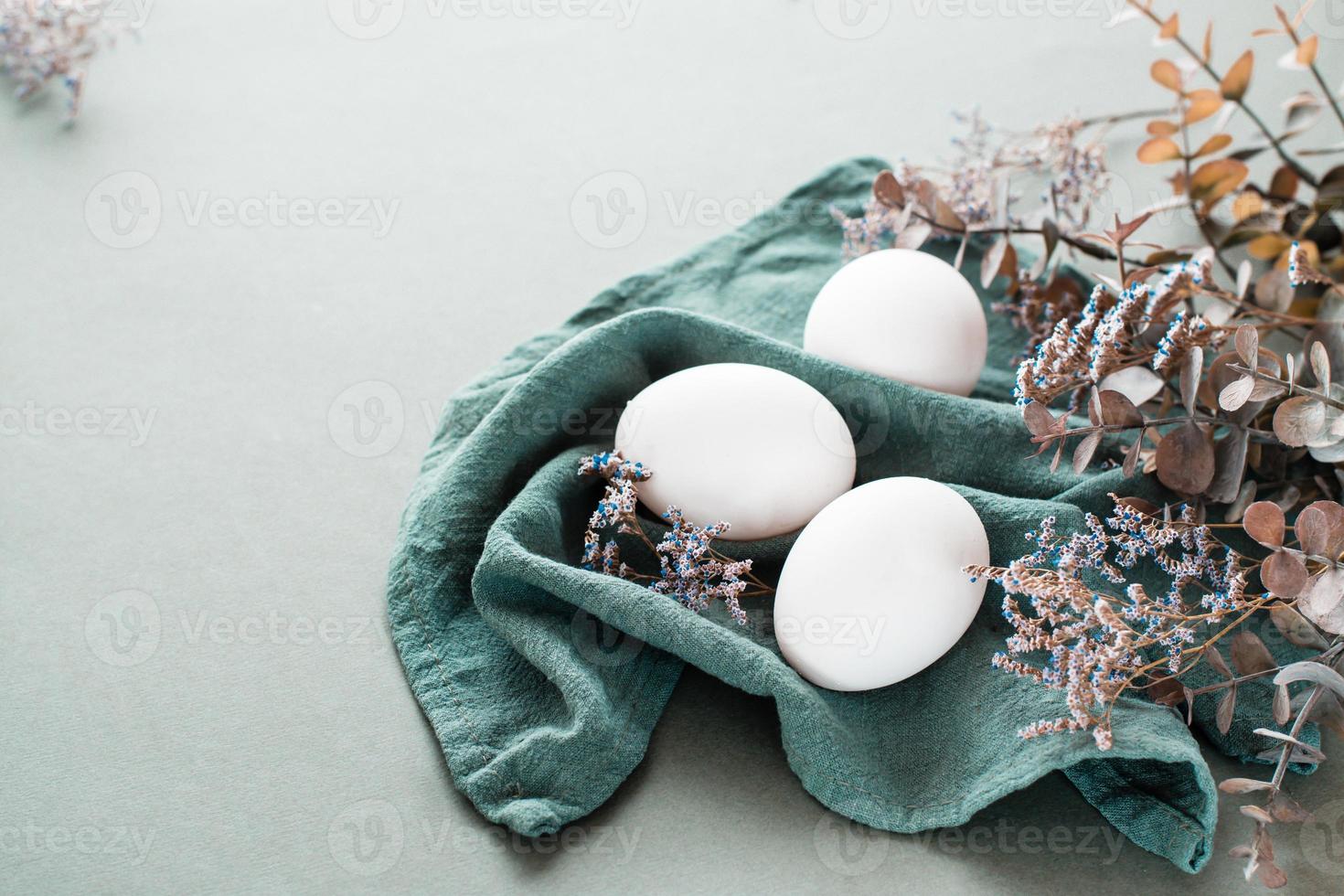 bianca pollo uova su un' biancheria tovagliolo e un' ramo di eucalipto e gypsophila su un' verde sfondo. eco amichevole contento Pasqua. foto