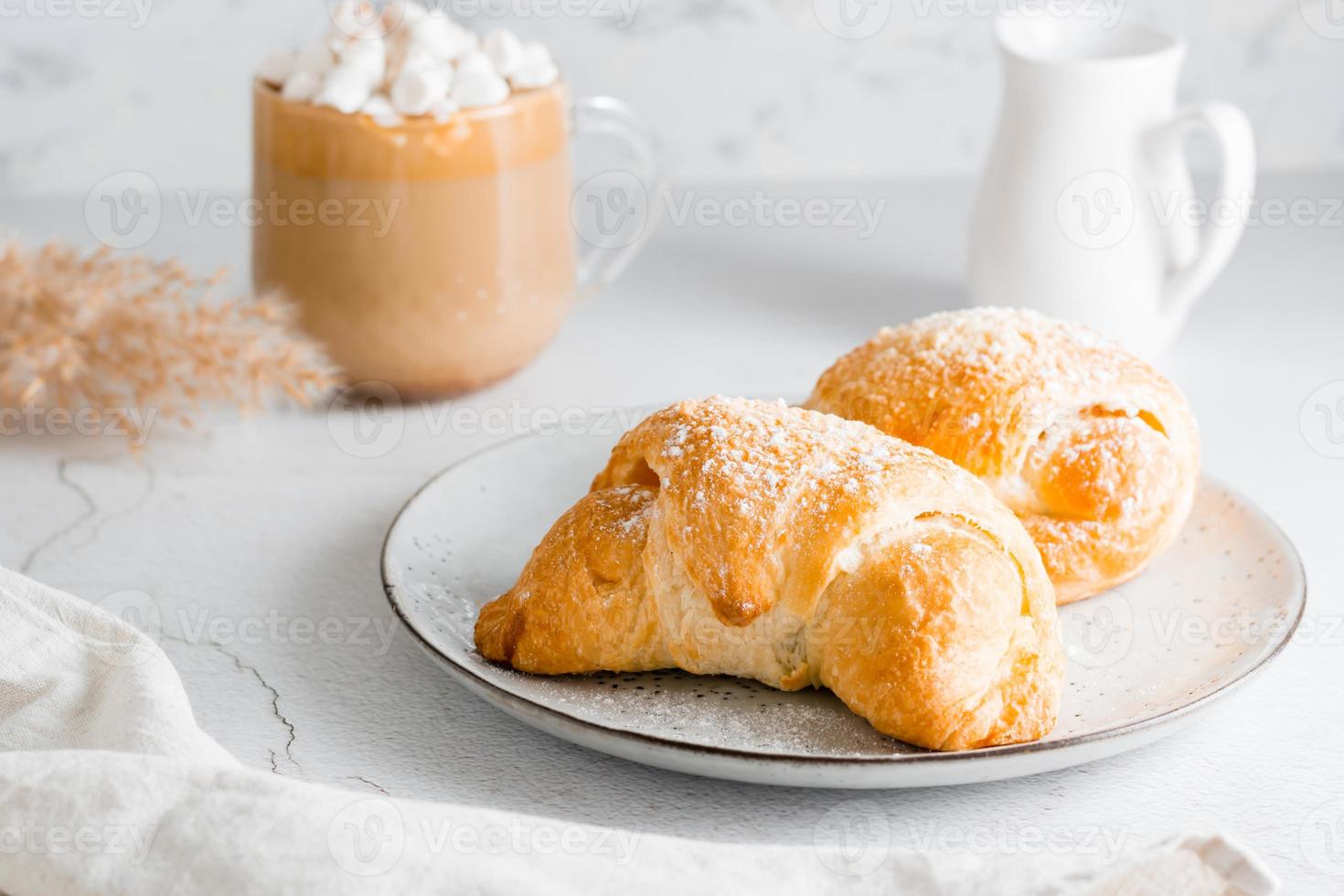 Cornetti su un' piatto e delizioso caffè con marshmallows nel un' tazza su il tavolo. stile di vita fatti in casa merenda. avvicinamento foto