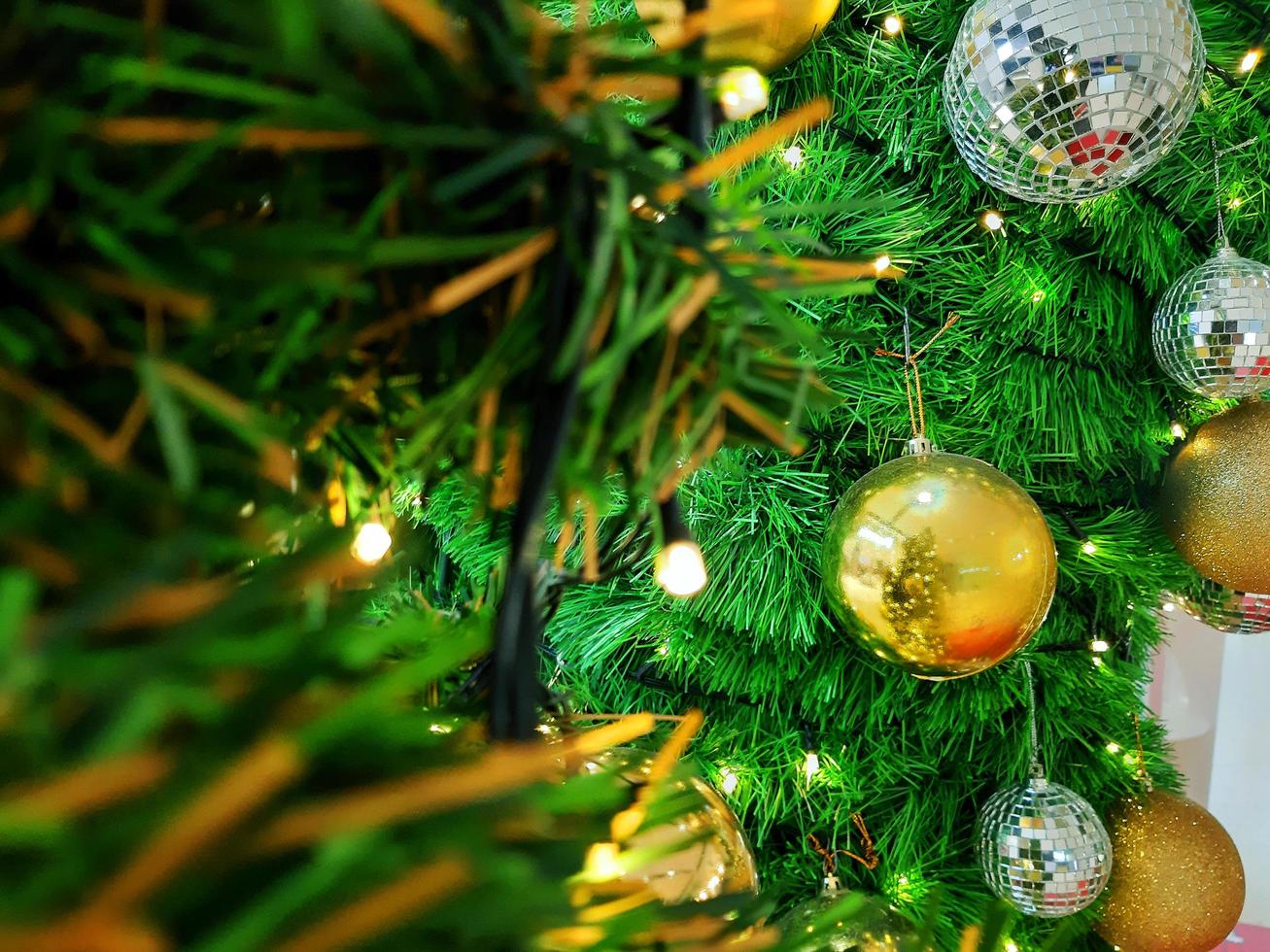 palla di Natale appesa a rami di pino con uno sfondo festivo foto