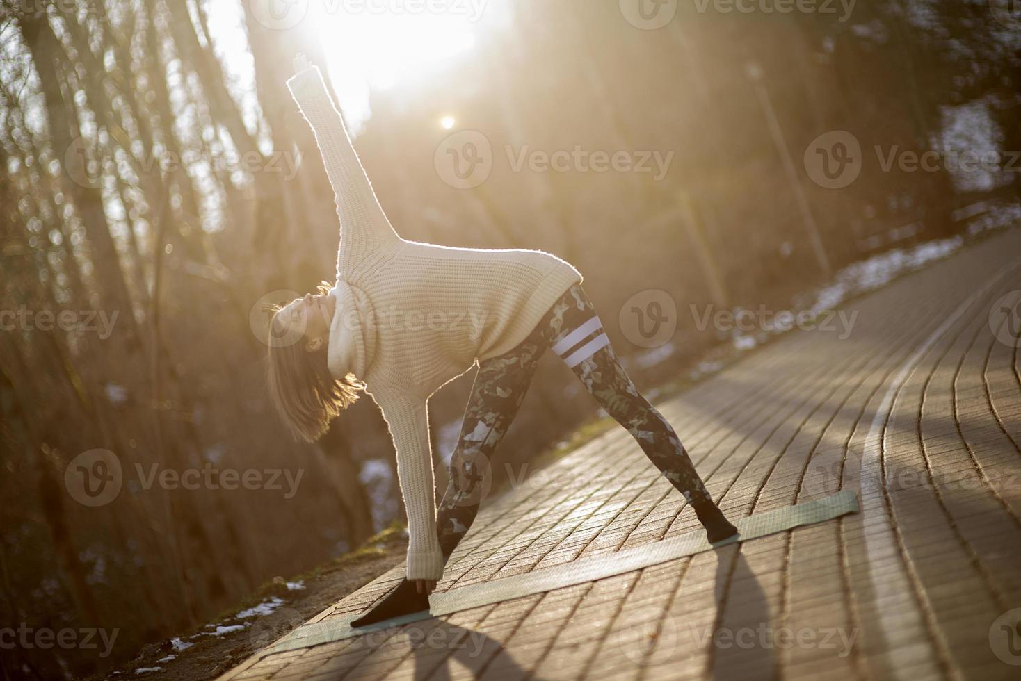 una giovane donna atletica esegue esercizi di yoga e meditazione all'aperto foto