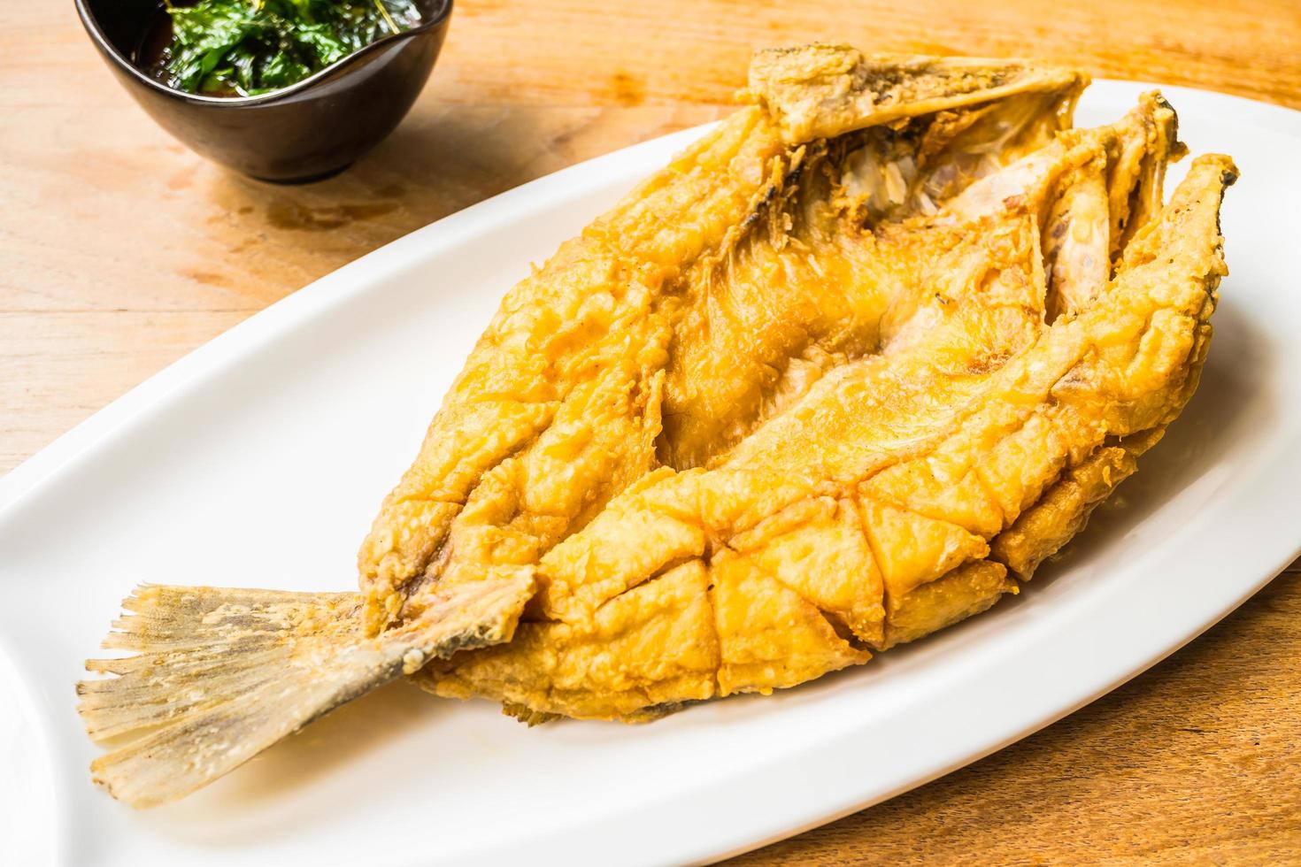 pesce di branzino fritto sul piatto bianco foto