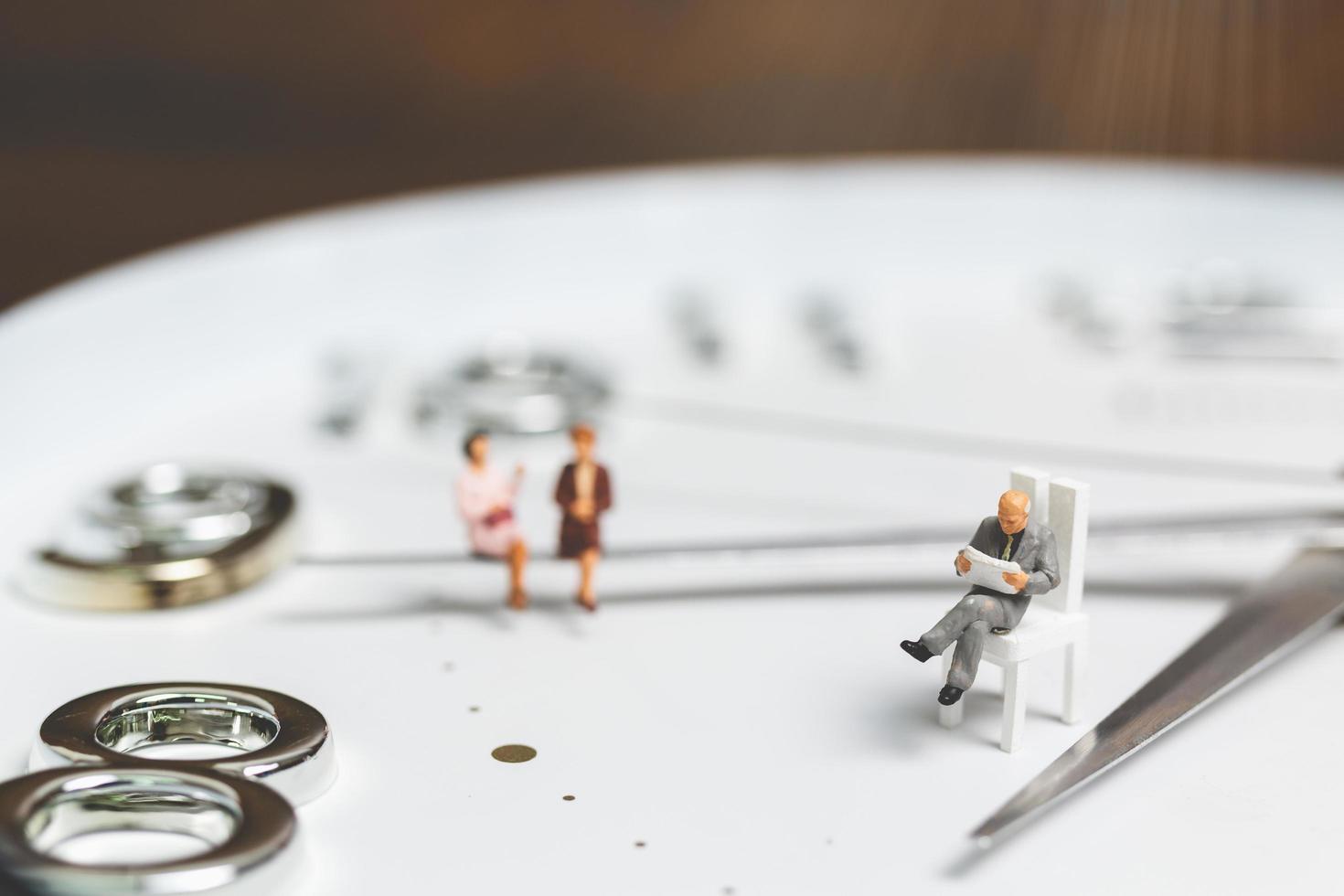 imprenditori in miniatura seduti su un orologio, il concetto di tempo e di lavoro foto