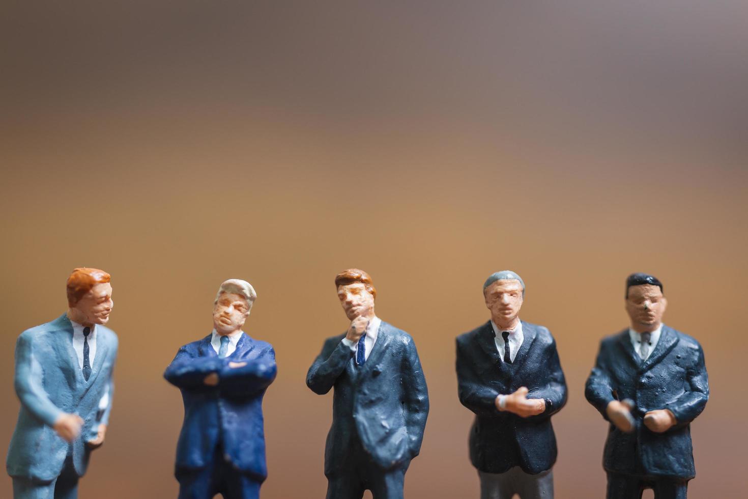uomini d'affari in miniatura in piedi su uno sfondo di legno, leader aziendale e concetto di lavoro di squadra foto