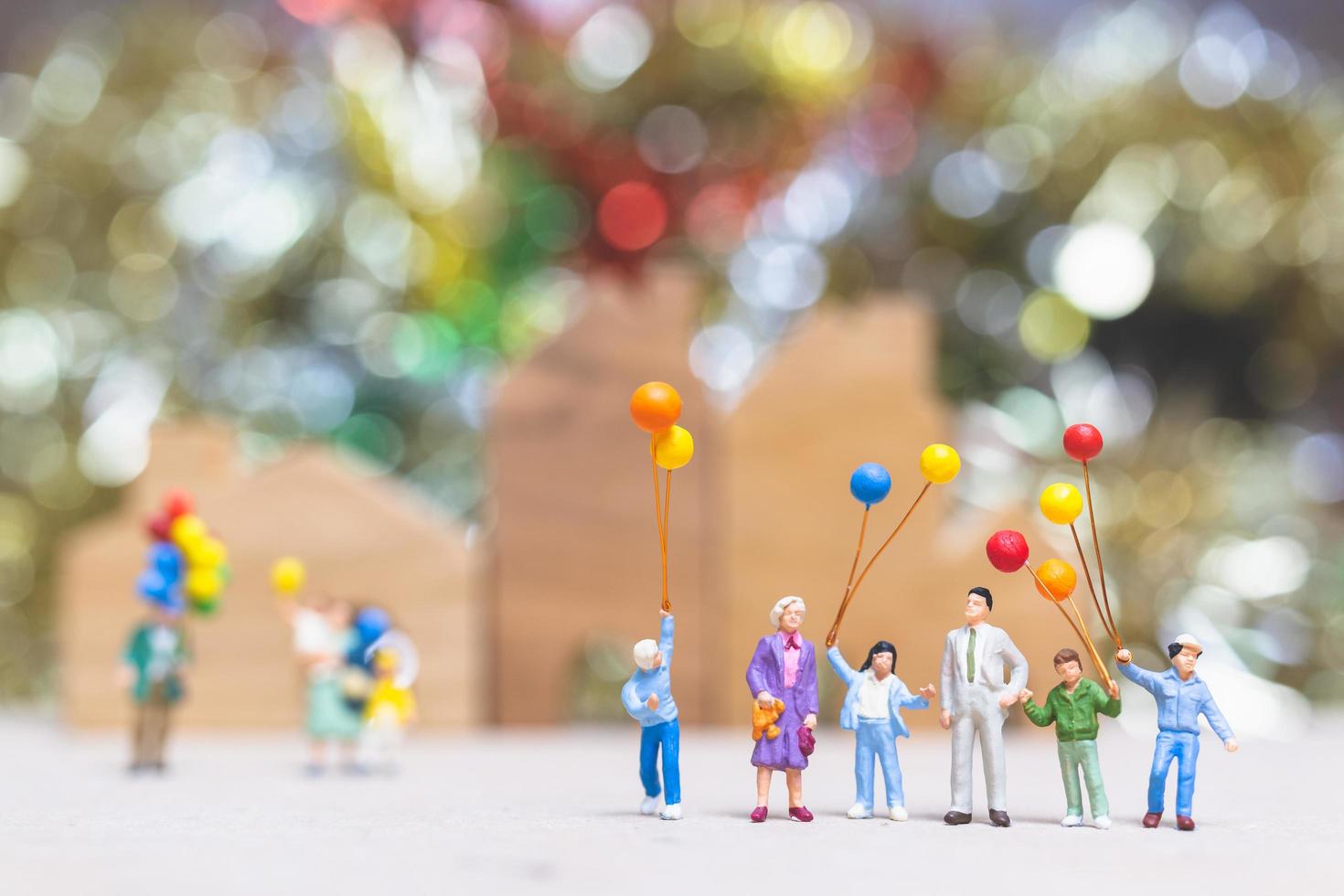 persone in miniatura che tengono palloncini in un parco con uno sfondo colorato bokeh, relazioni familiari felici e concetto di tempo libero spensierato foto