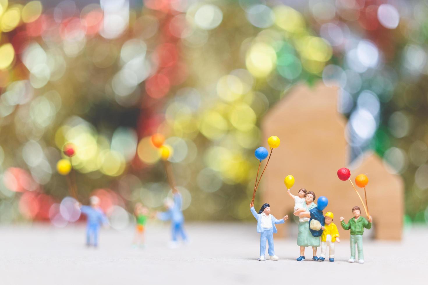 persone in miniatura che tengono palloncini in un parco con uno sfondo colorato bokeh, relazioni familiari felici e concetto di tempo libero spensierato foto