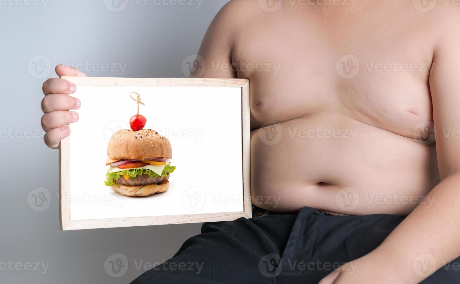 Grasso ragazzo mostrare Hamburger immagine su lavagna foto