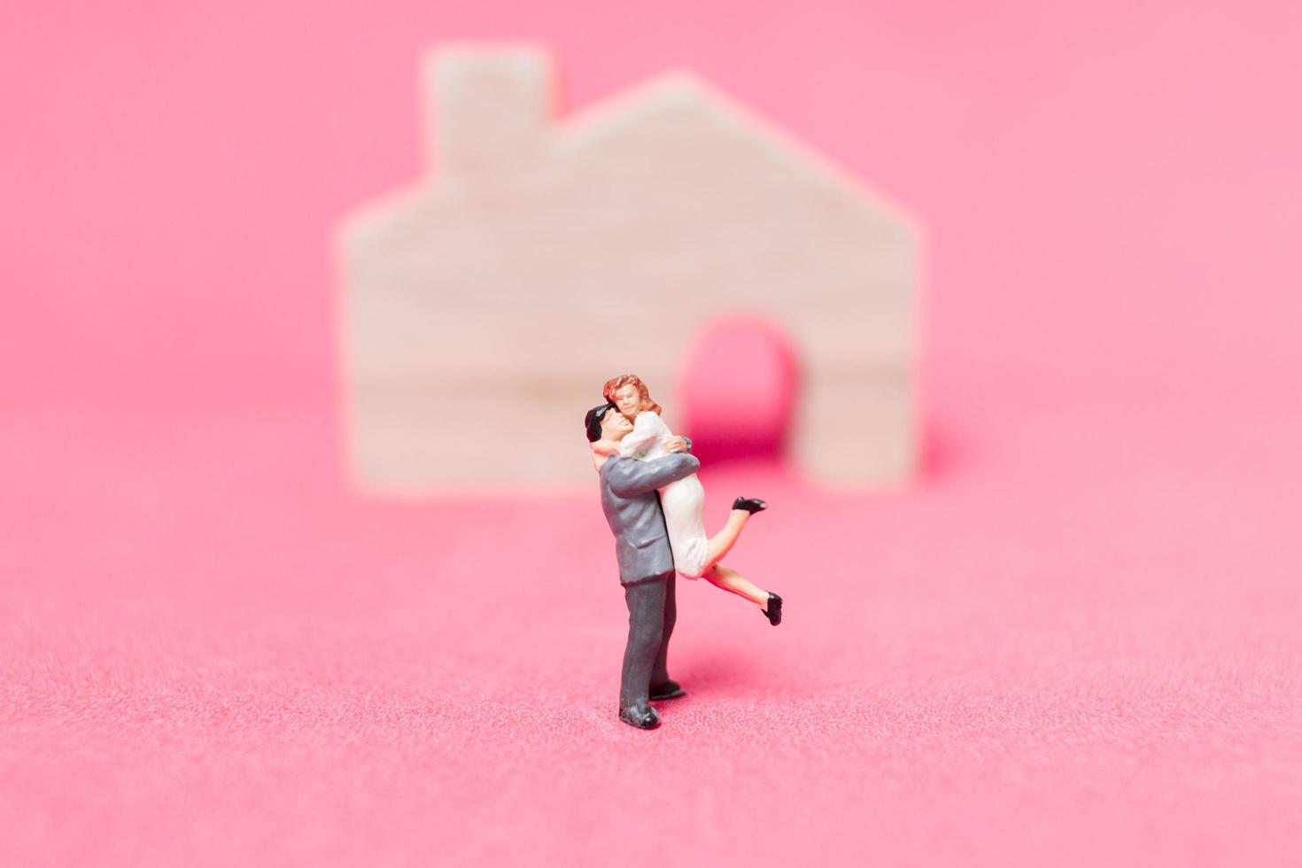 coppia in miniatura con case su uno sfondo rosa, concetto di San Valentino foto