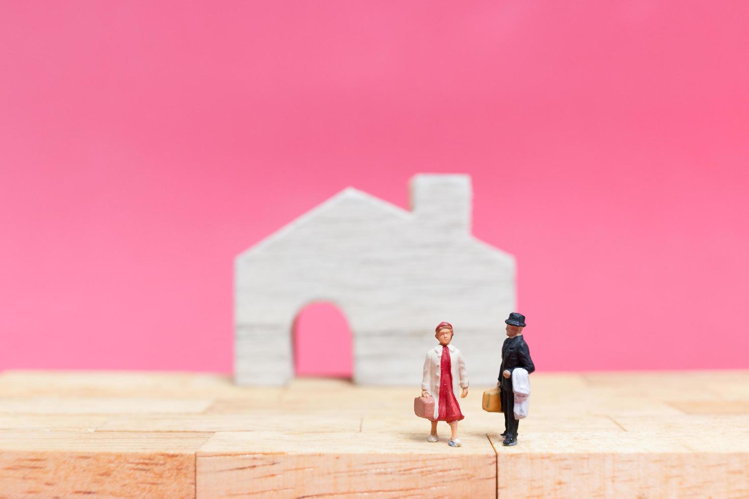 coppia in miniatura con case su uno sfondo rosa, concetto di San Valentino foto