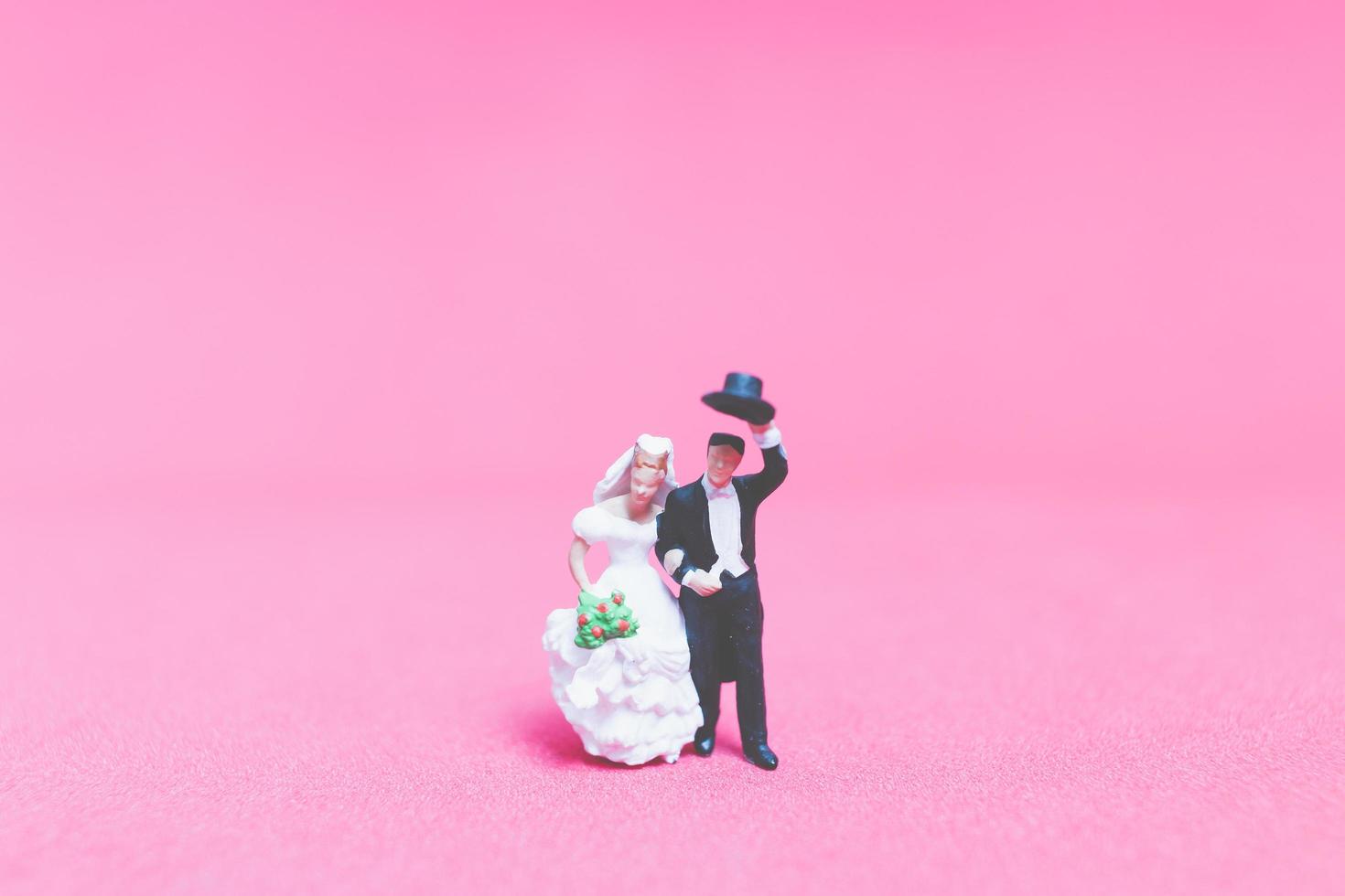 matrimonio in miniatura, una sposa e lo sposo su uno sfondo rosa foto