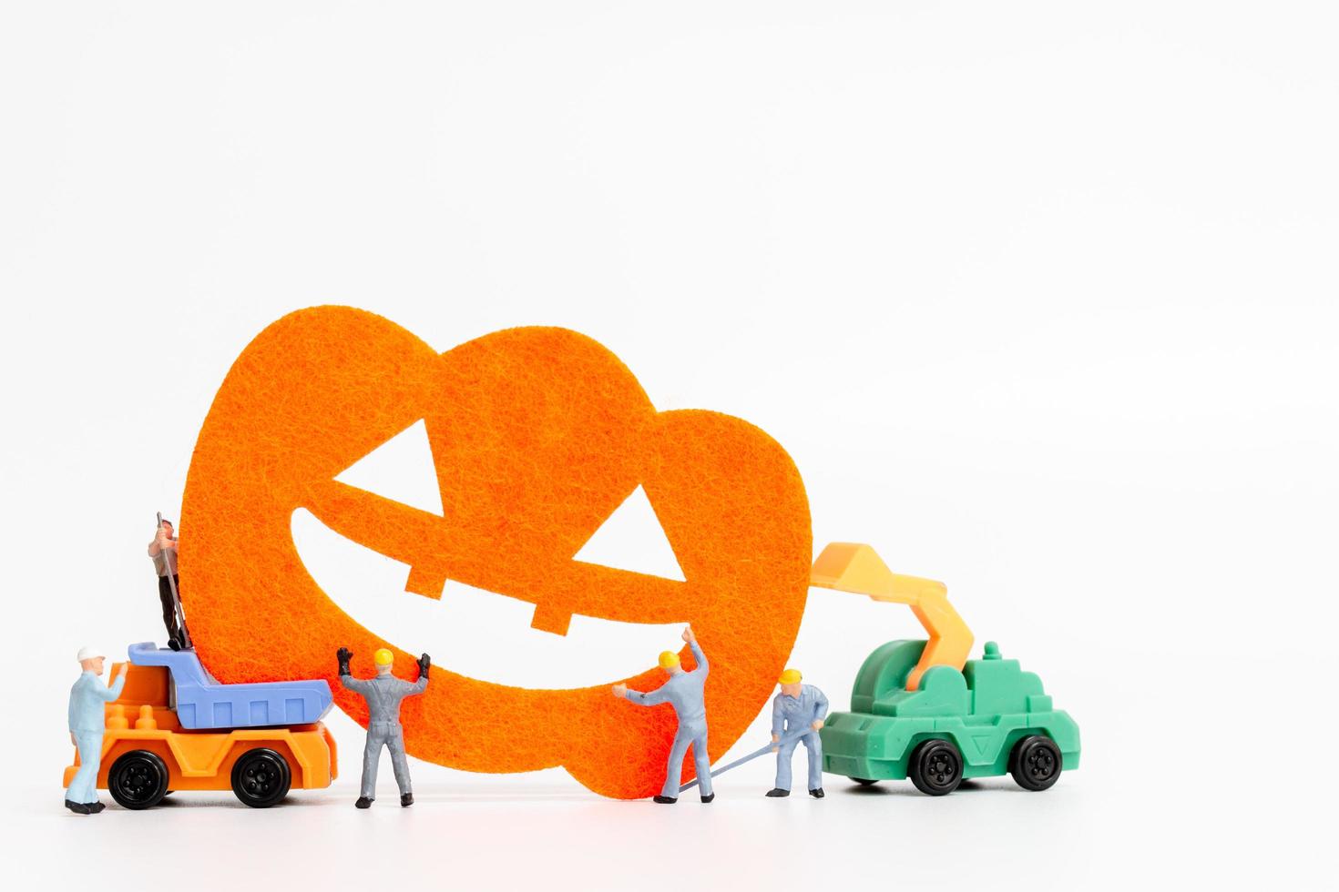 lavoratori in miniatura che collaborano per creare oggetti di scena per la festa di Halloween su uno sfondo bianco foto