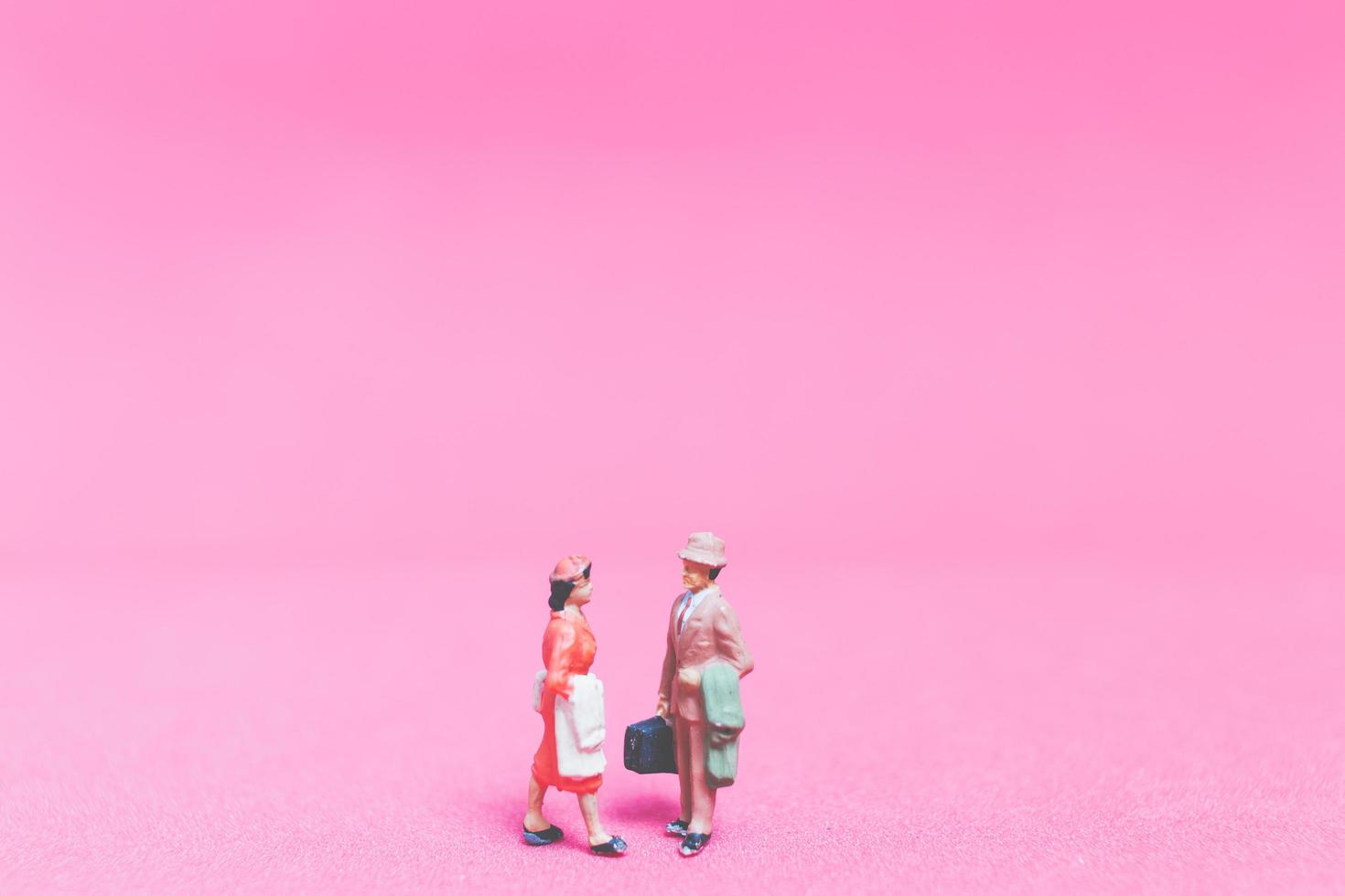 coppia in miniatura di viaggiatori su uno sfondo rosa foto
