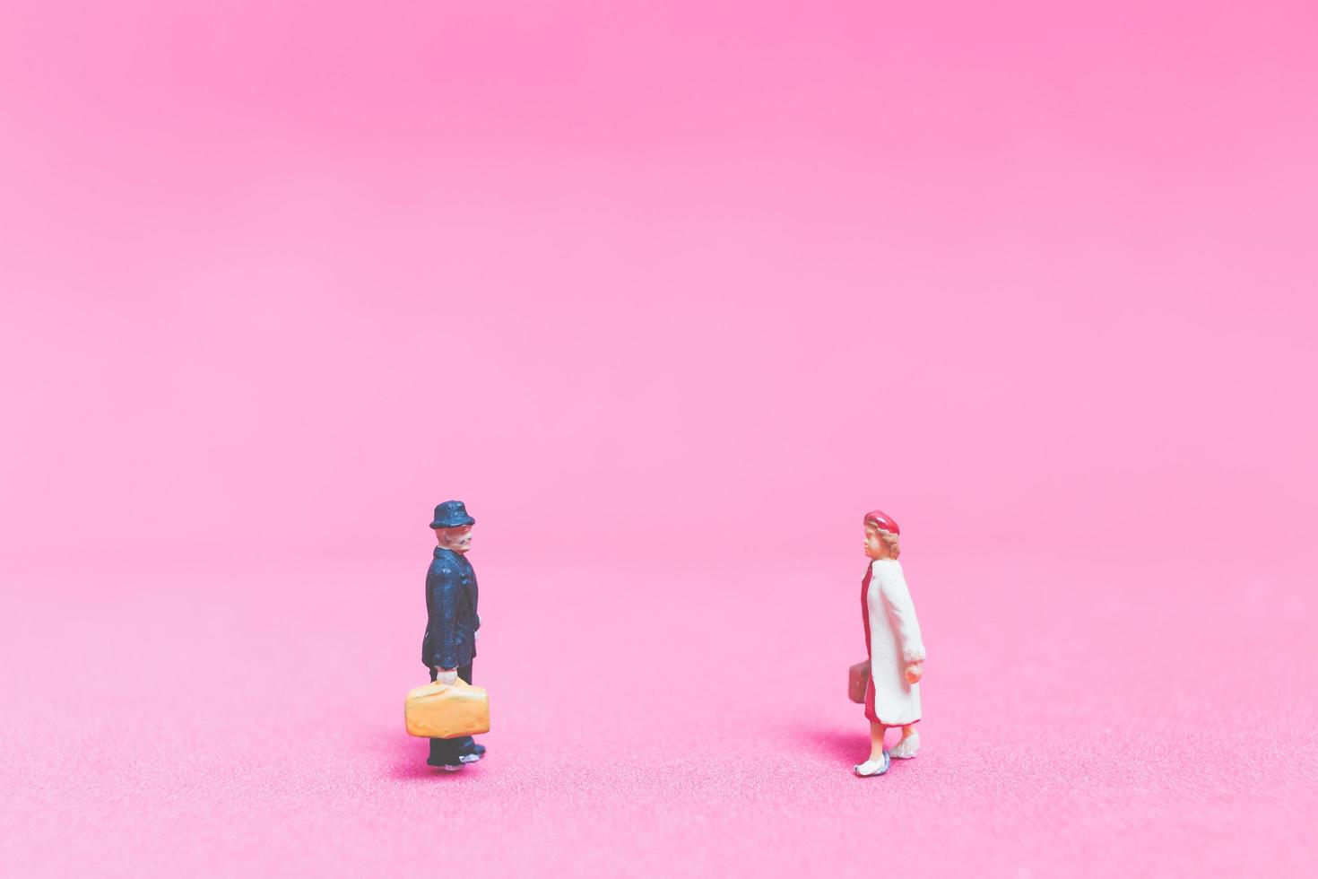 coppia in miniatura di viaggiatori su uno sfondo rosa foto