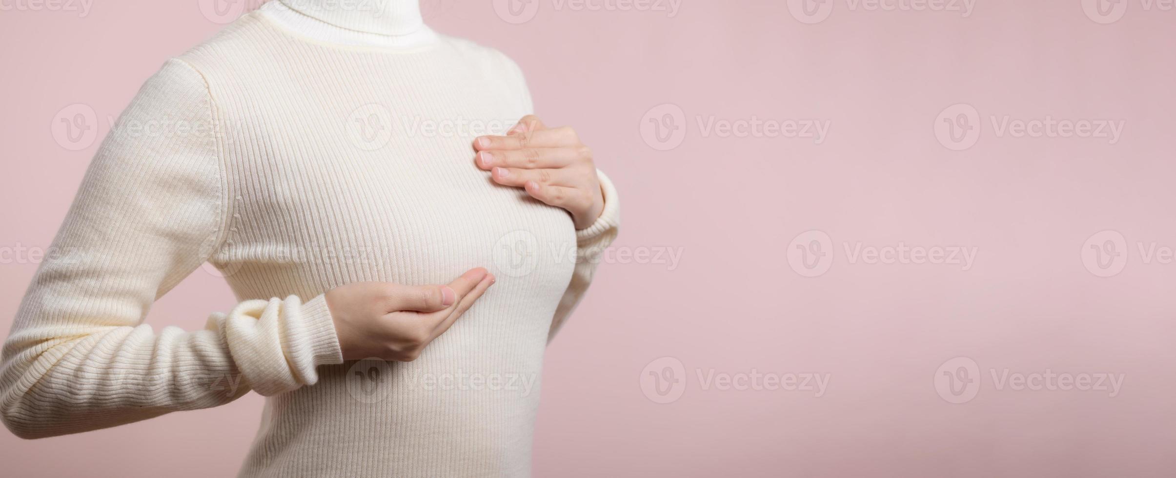 donna mani controllo granuli su sua Seno per segni di Seno cancro su rosa sfondo. assistenza sanitaria concetto. foto