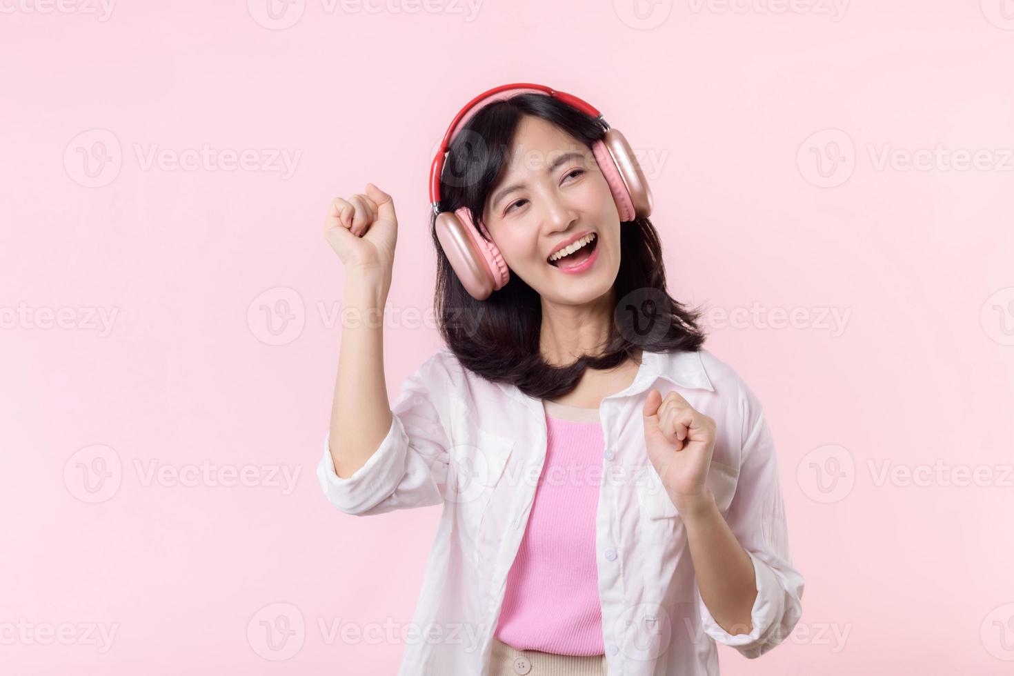 Sorridi bella asiatico modello persona ascolta musica canzone e godere danza con senza fili cuffie in linea Audio Radio suono. positivo divertimento Uscito gioioso gioventù femmina donna su rosa isolato sfondo studio foto