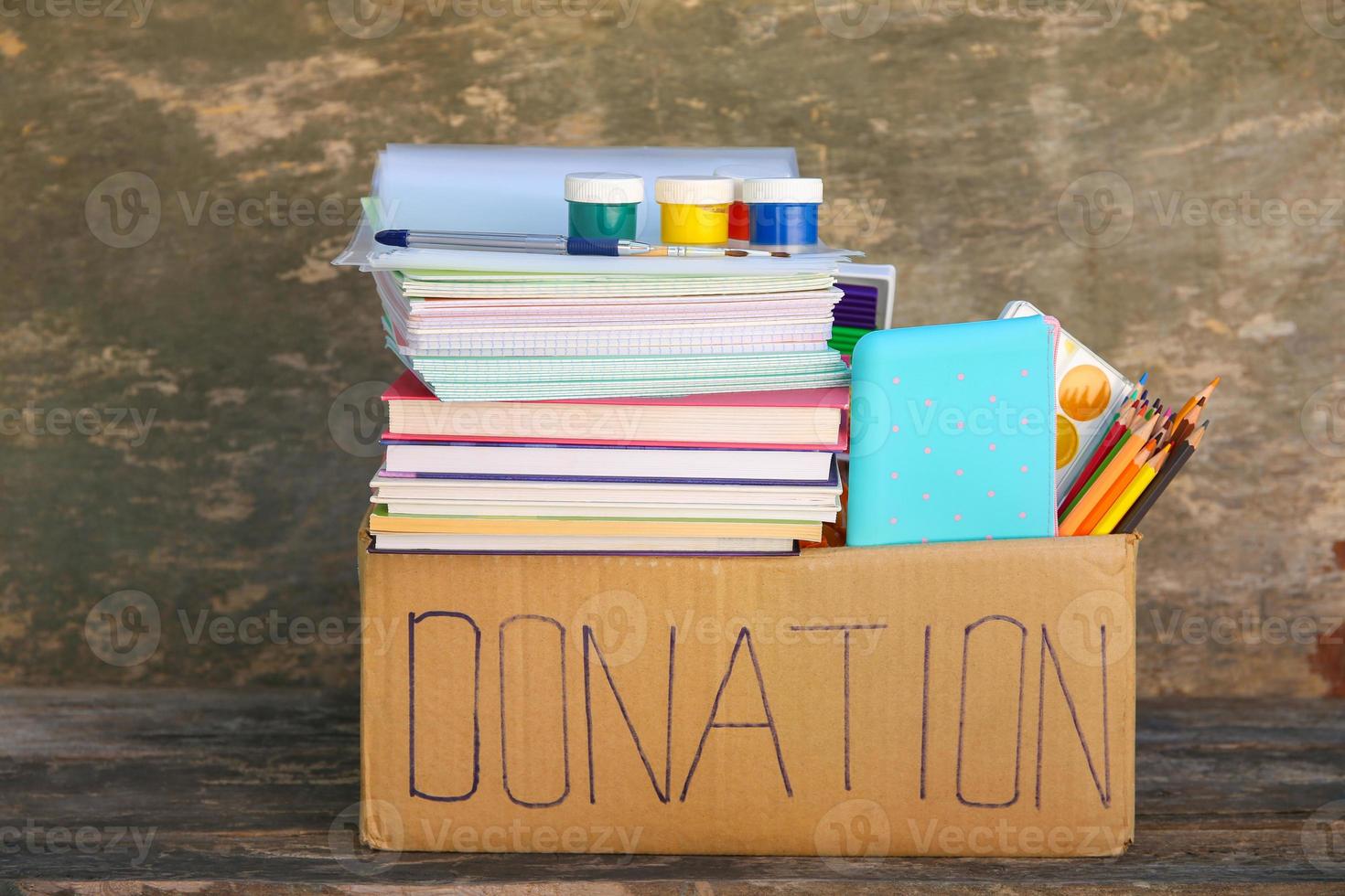 donazione scatola con scuola forniture su vecchio di legno sfondo. foto