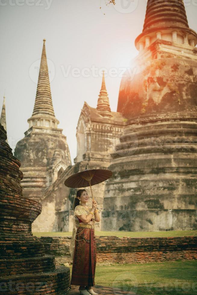 asiatico donna Tenere bambù ombrello in piedi contro stupa nel antico tempio di ayutthaya mondo eredità luogo di unesco centrale di Tailandia foto