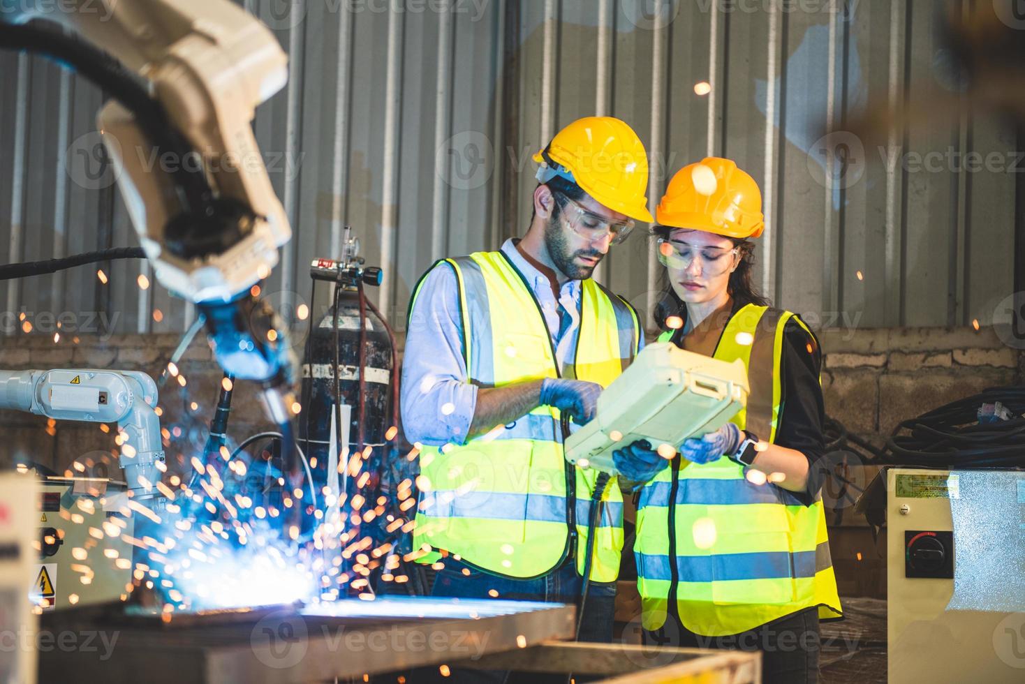 Due ingegneri meccanico utilizzando computer controllore robotica braccio per saldatura acciaio nel acciaio fabbrica officina. industria robot programmazione Software per automatizzato produzione tecnologia foto