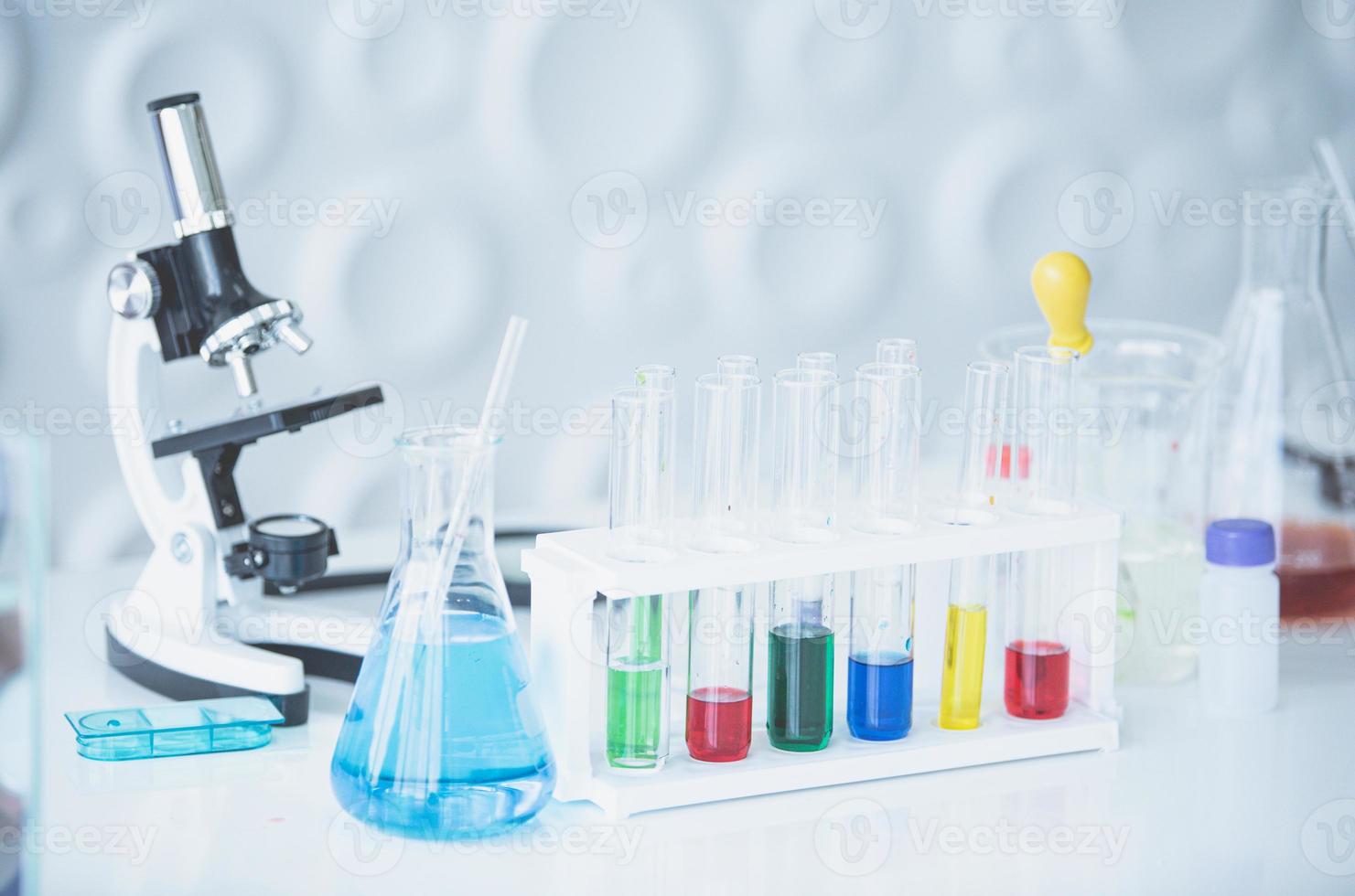 microscopio e colorato test tubi su tavolo nel laboratorio. scienza chimica concetto. blu tono foto