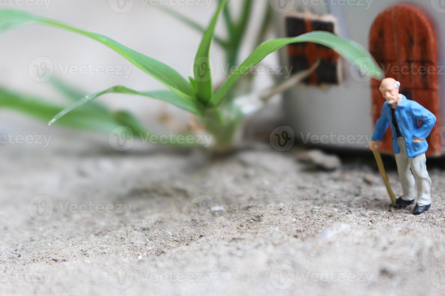 miniatura figura di un' nonno chi è in attesa nel davanti di il Casa. foto