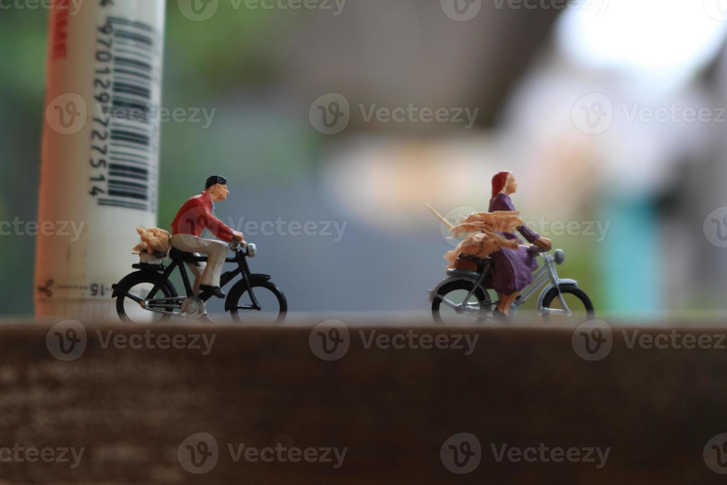 bogor, Indonesia - dicembre, 12 2022. miniatura figure di Due ciclisti attraversamento un' di legno strada. foto