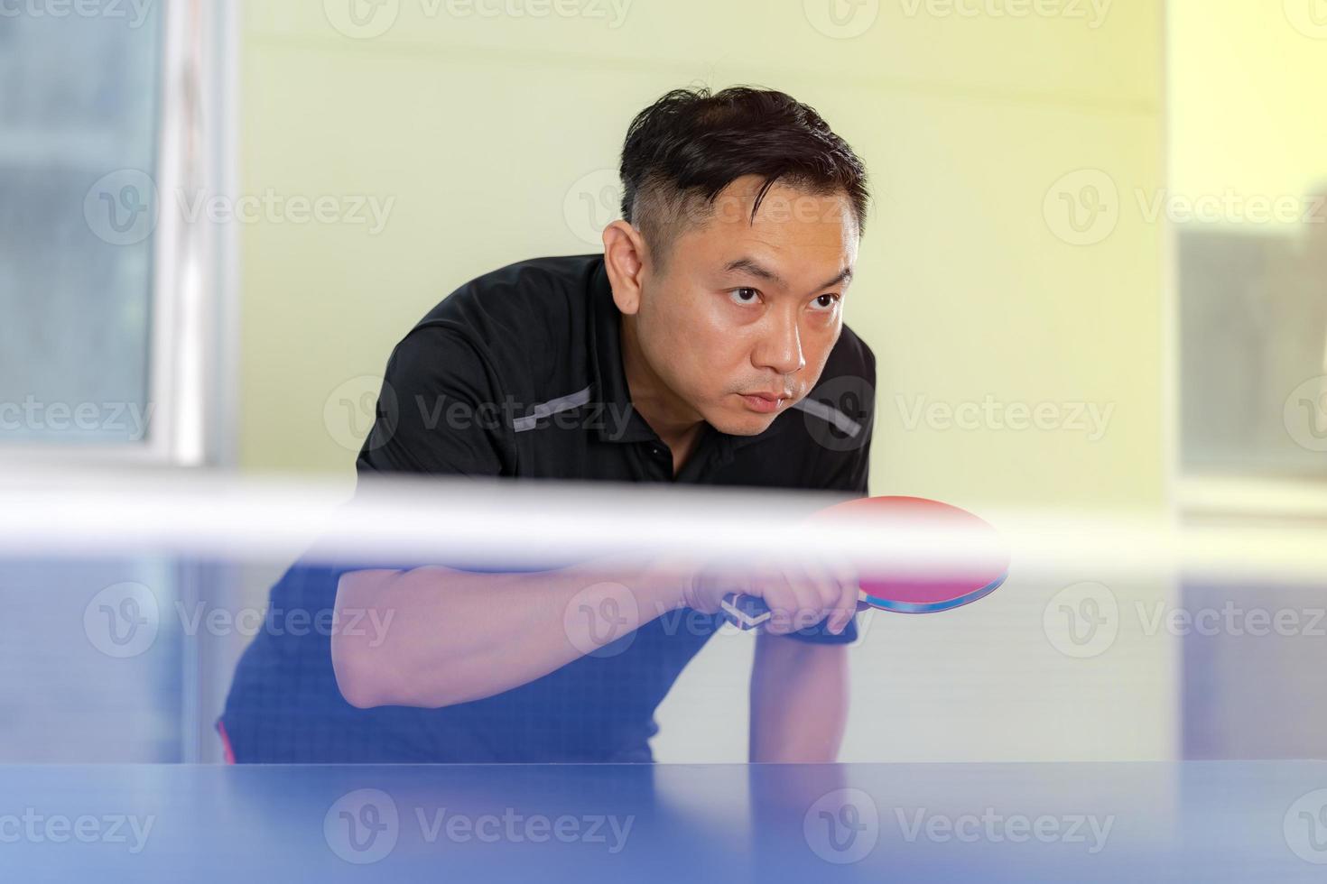 maschio giocando a ping pong con racchetta e palla in un palazzetto dello sport foto