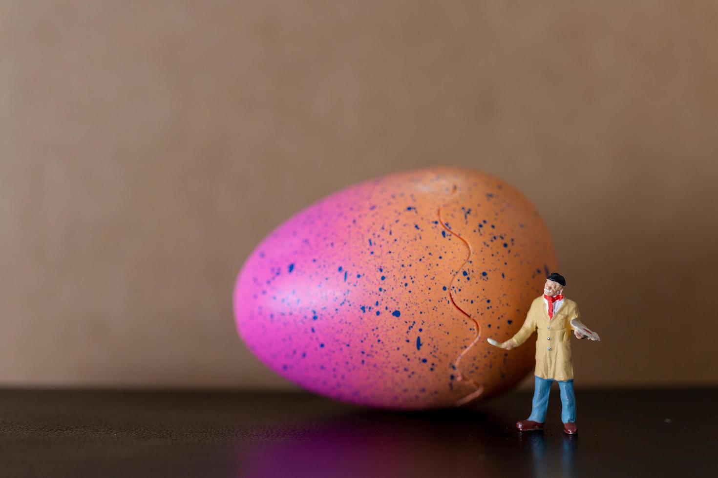 artista in miniatura che tiene un pennello e dipinge le uova di Pasqua per la Pasqua foto