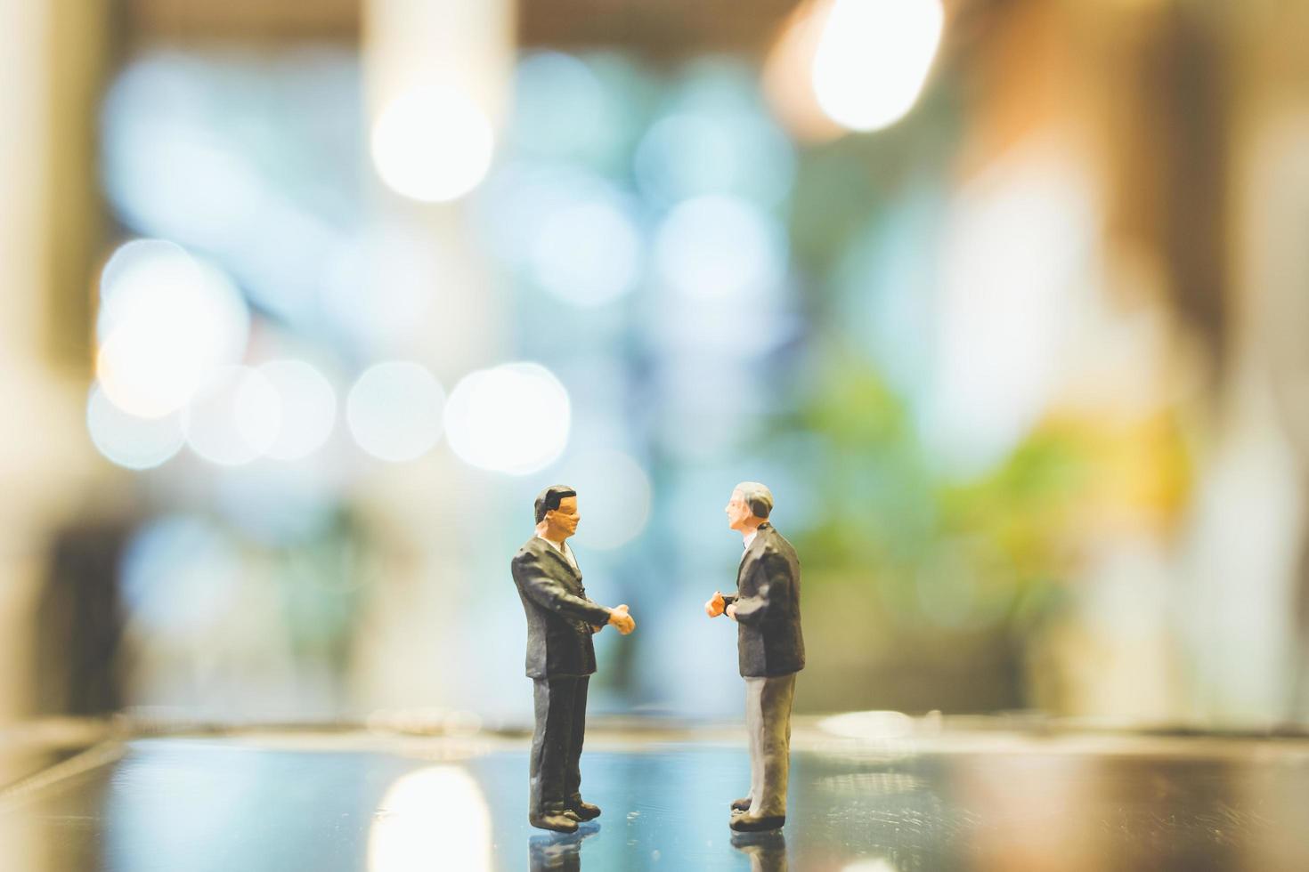 uomini d'affari in miniatura in piedi sul vetro con uno sfondo sfocato foto
