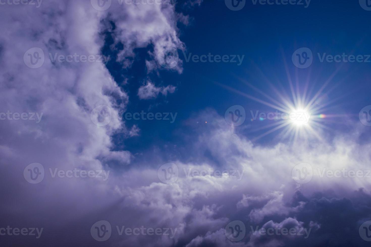 naturale sole brilla al di sopra di nuvole nel in profondità blu tempestoso cielo foto