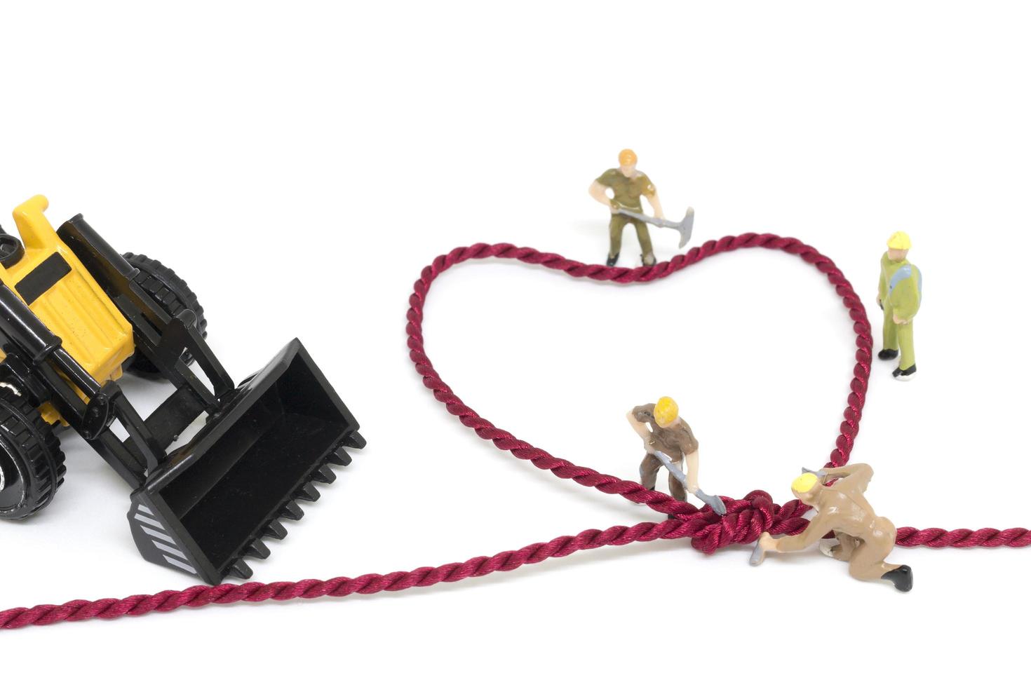 lavoratori in miniatura che costruiscono una corda a forma di cuore su uno sfondo bianco foto