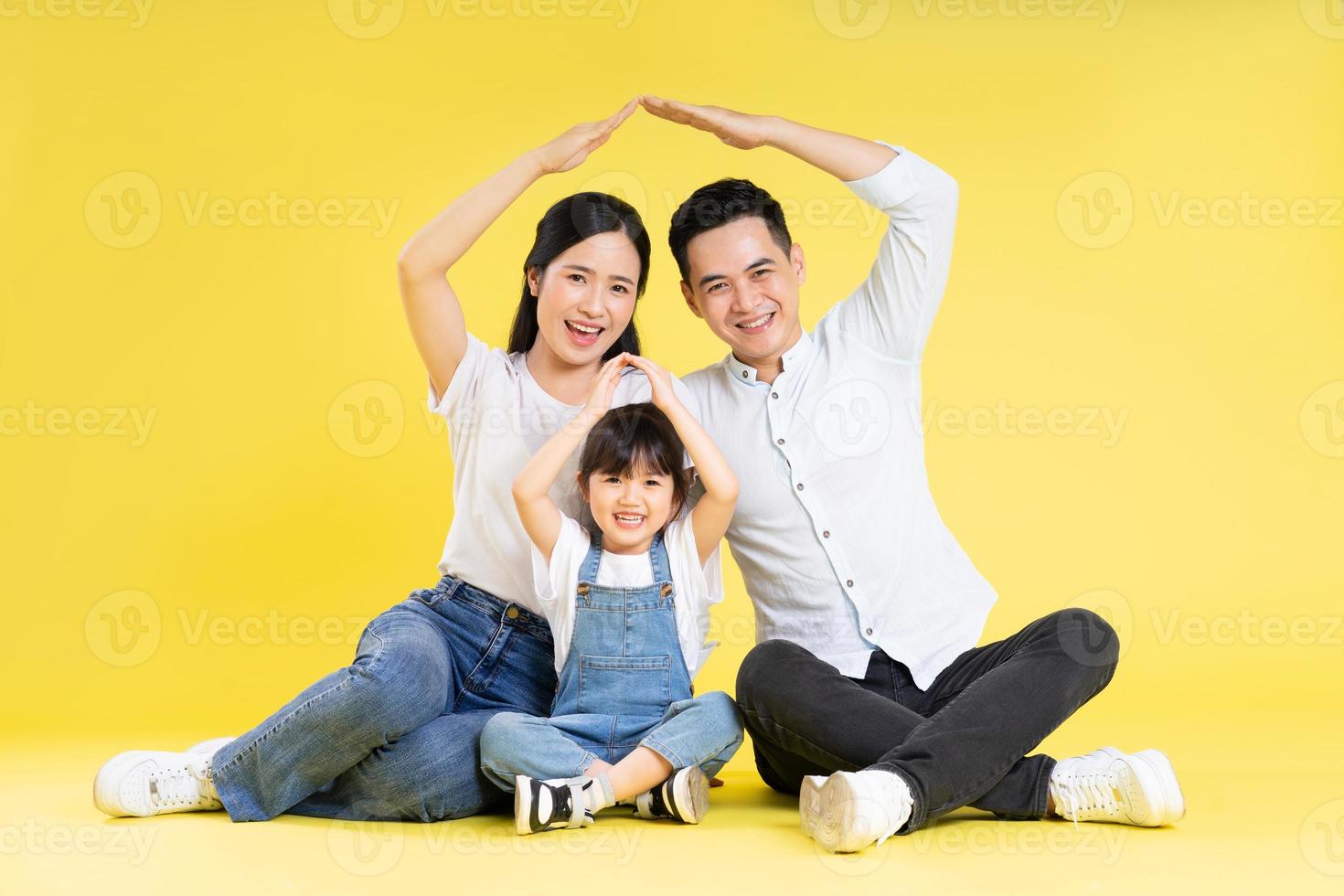 Immagine di asiatico famiglia seduta insieme contento e isolato su giallo sfondo foto