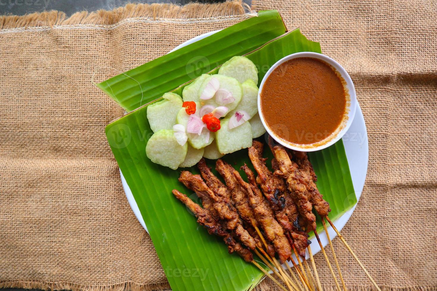 pollo satay o pollo satay servito con lungo, riso torta e arachide salsa. servito su Banana partire foto