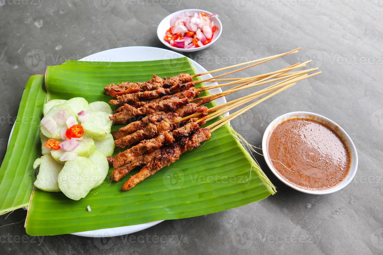 pollo satay o pollo satay servito con lungo, riso torta e arachide salsa. servito su Banana partire foto