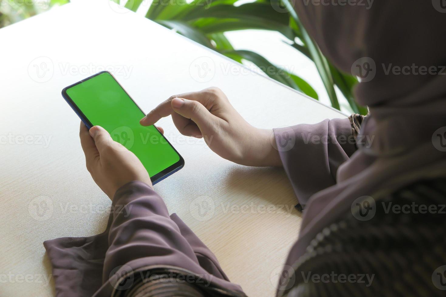 donna che utilizza uno smart phone con schermo verde foto