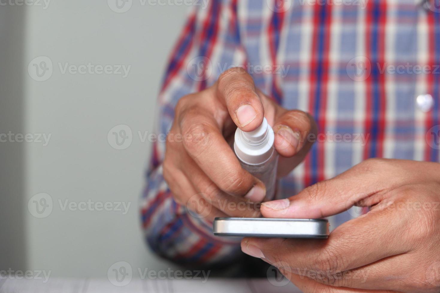 disinfettare lo schermo di uno smartphone con disinfettante foto