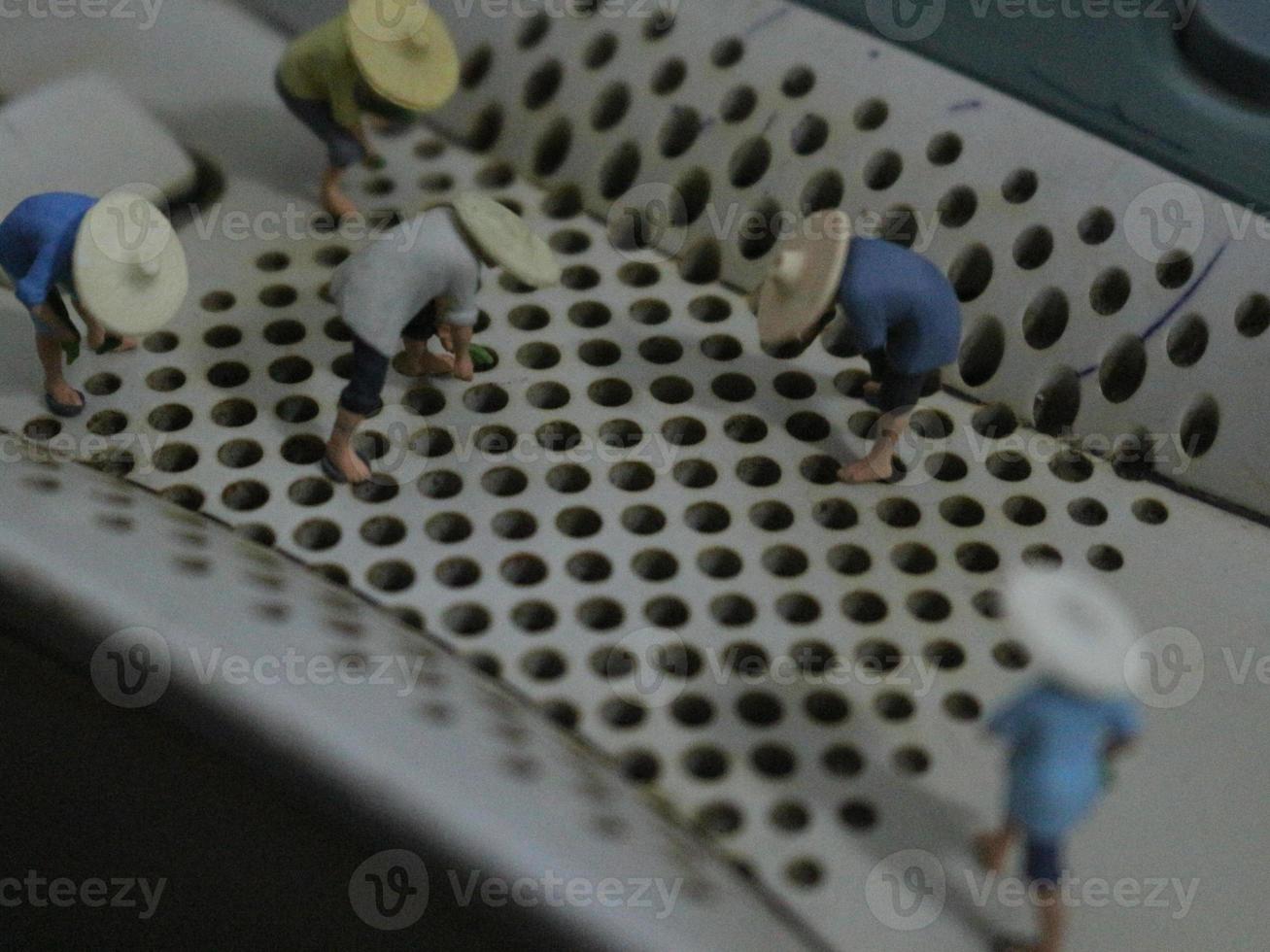 miniatura figure di agricoltori coltivando colture nel il telefono di estensione altoparlante buco. foto