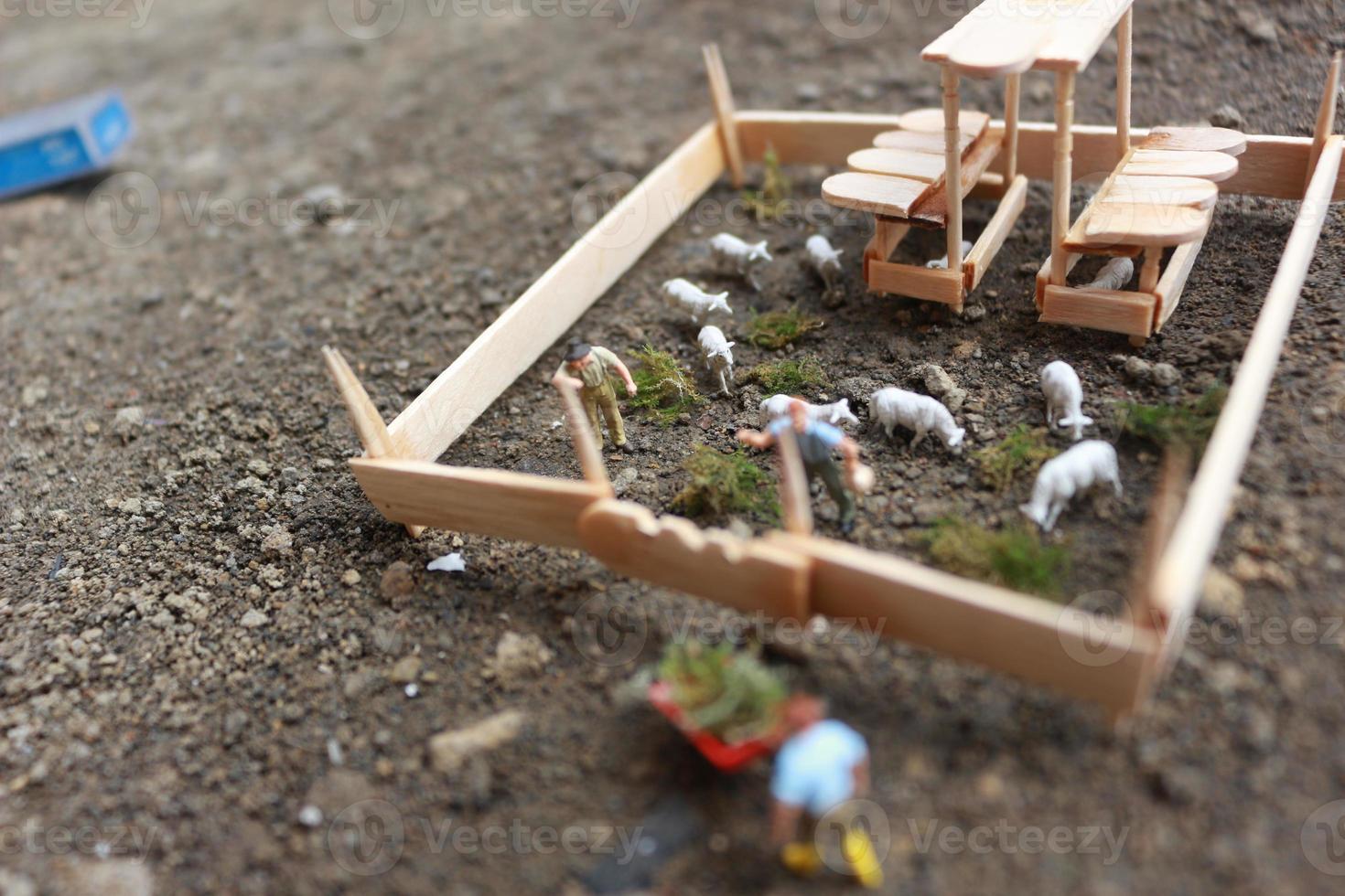 un' vicino su di miniatura figura di un' capra Herder alimentazione nel un' di legno gabbia. pastore concetto. foto