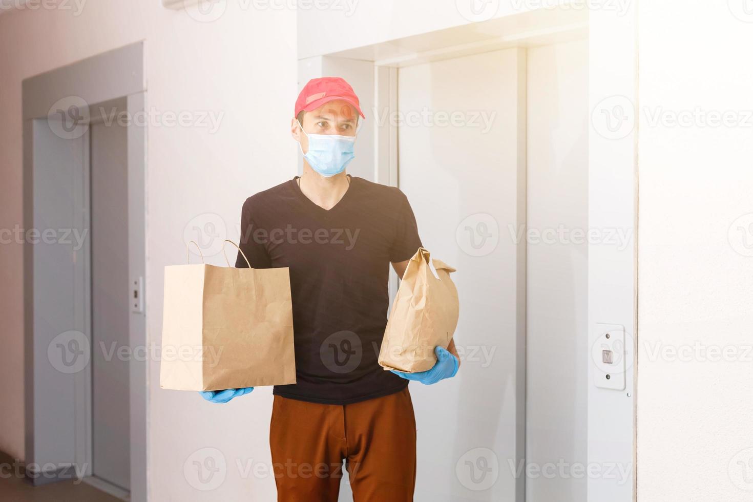 Corriere nel protettivo maschera e medico guanti consegna porta via cibo. consegna servizio sotto quarantena, malattia scoppio, coronavirus covid-19 pandemia condizioni. foto