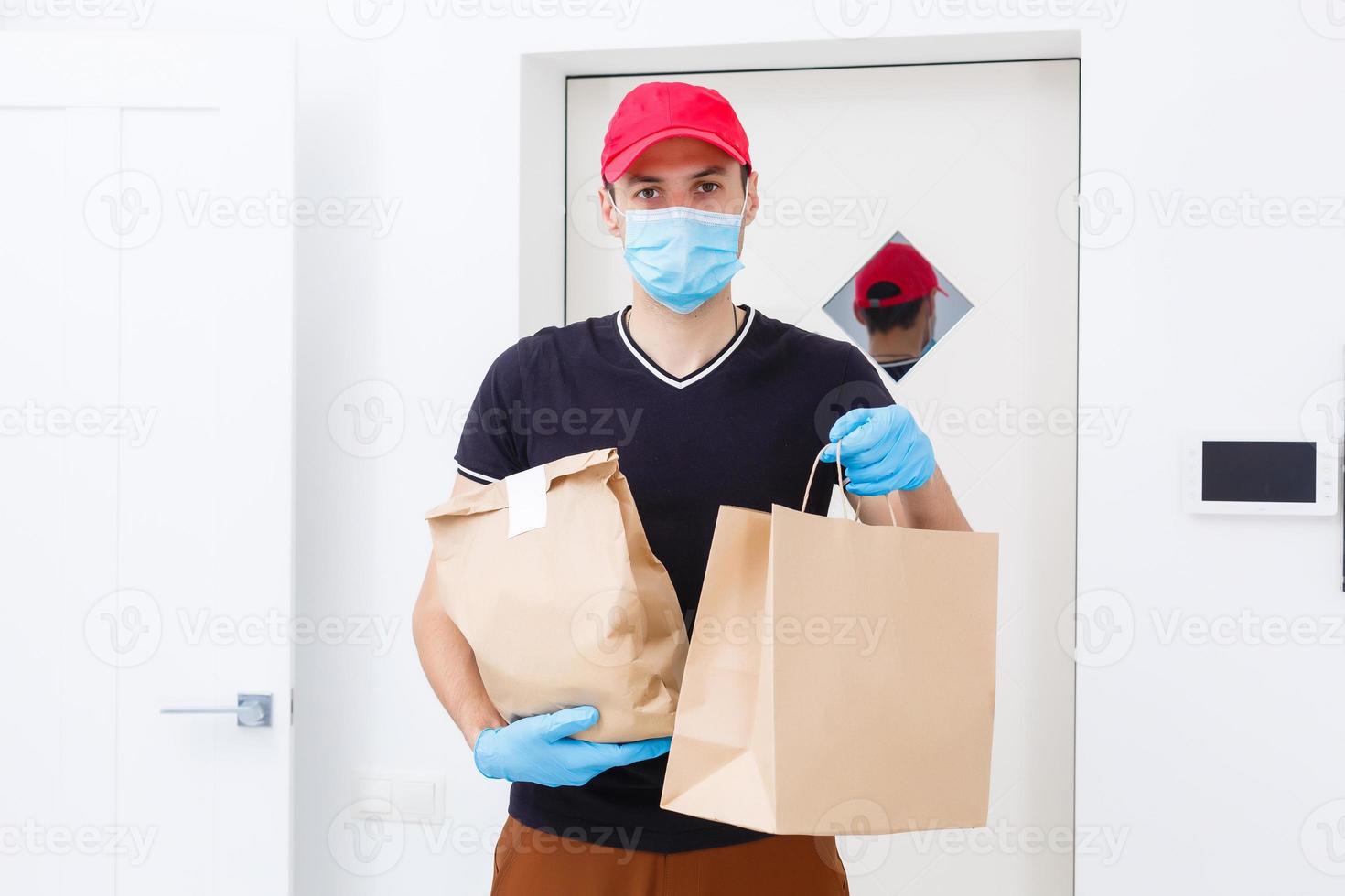 consegna uomo Tenere carta Borsa con cibo su bianca sfondo, cibo consegna uomo nel protettivo maschera e protettivo guanti foto