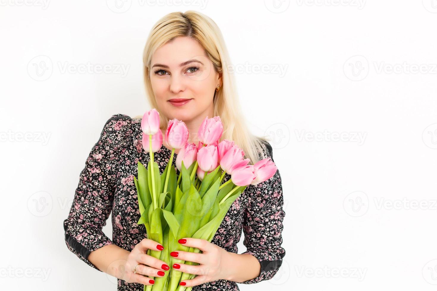 ritratto di un' bellissimo giovane ragazza nel vestito Tenere grande mazzo di tulipani al di sopra di bianca sfondo foto