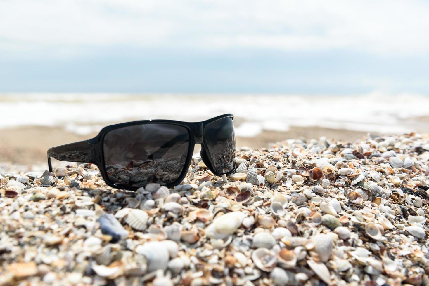 occhiali da sole in riva al mare foto