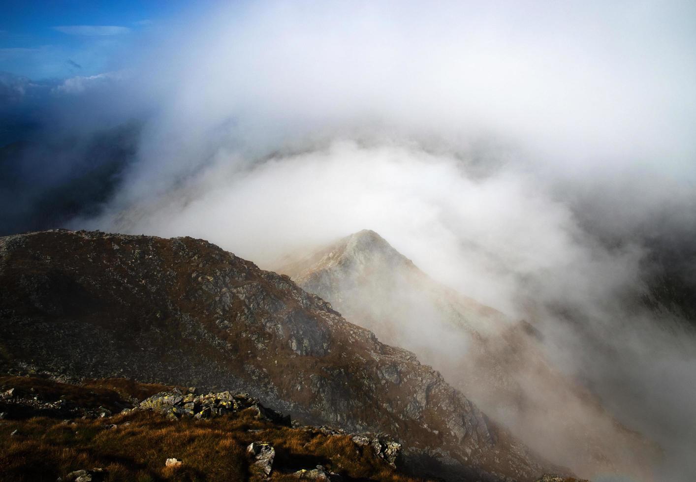 nebbia che giace sopra la cima della montagna foto