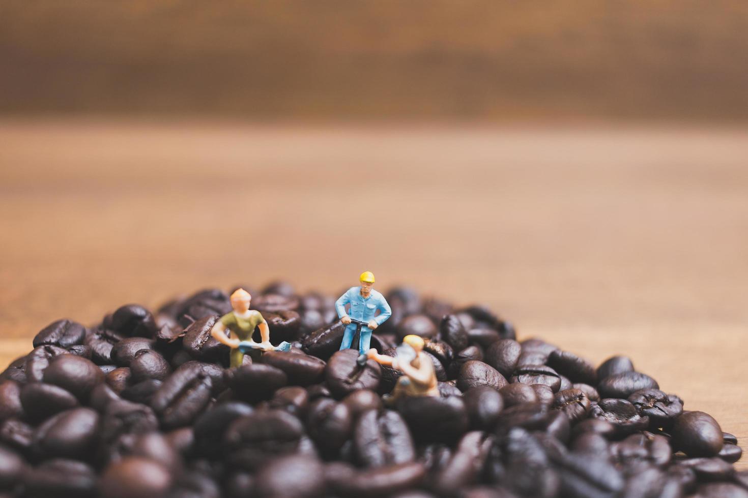 persone in miniatura che lavorano su chicchi di caffè tostati foto