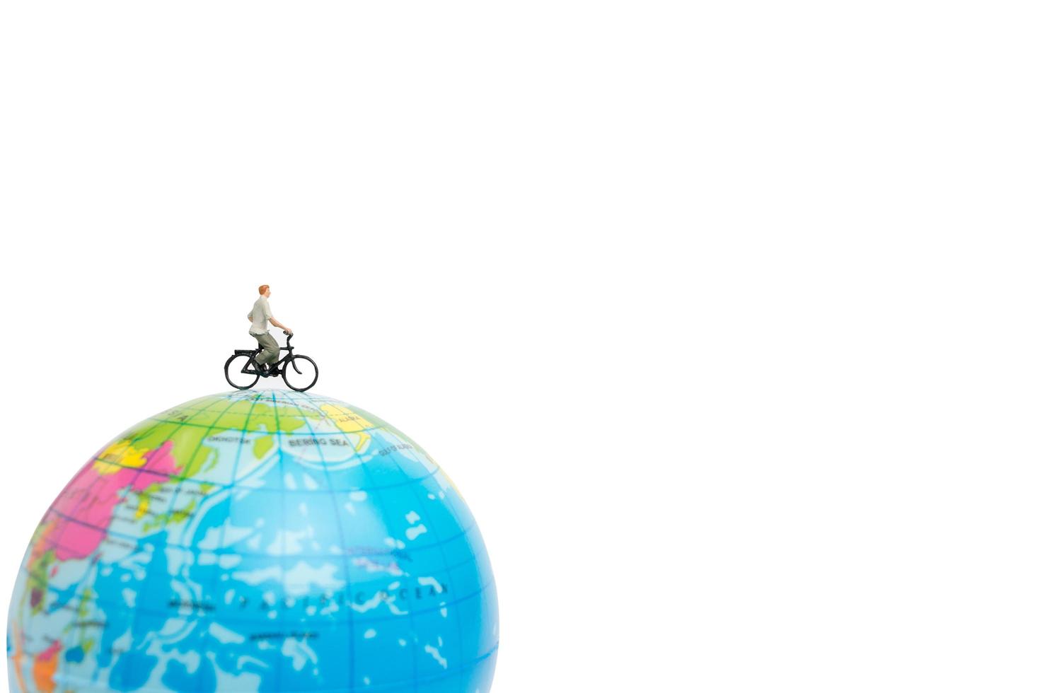 viaggiatore in miniatura con una bicicletta su un globo su uno sfondo bianco foto