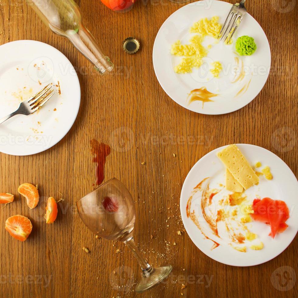 disordinato tavolo dopo festa. avanzi cibo, rovesciato bevande, sporco piatti. foto