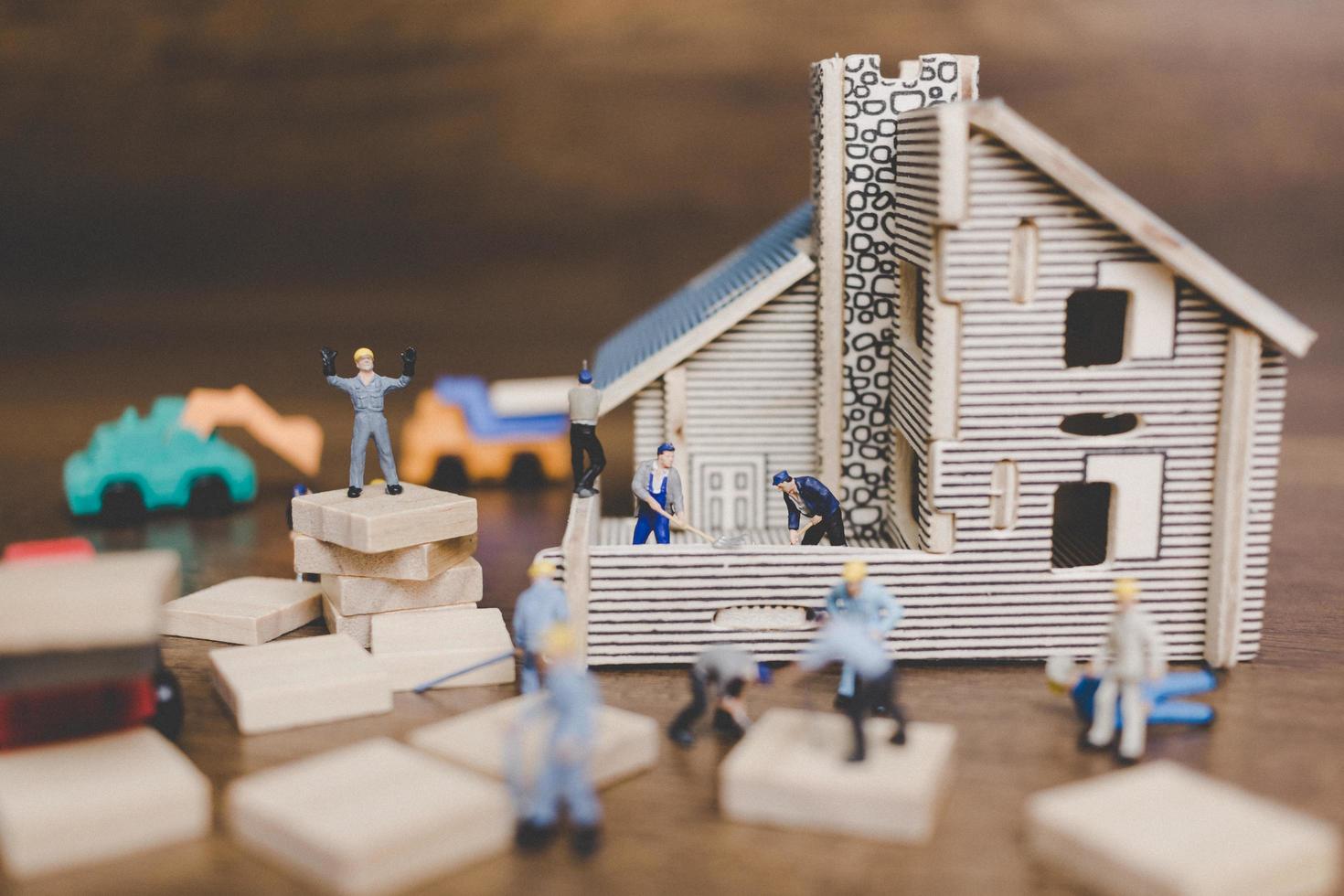 lavoratori in miniatura che riparano una casa su un fondo di legno foto