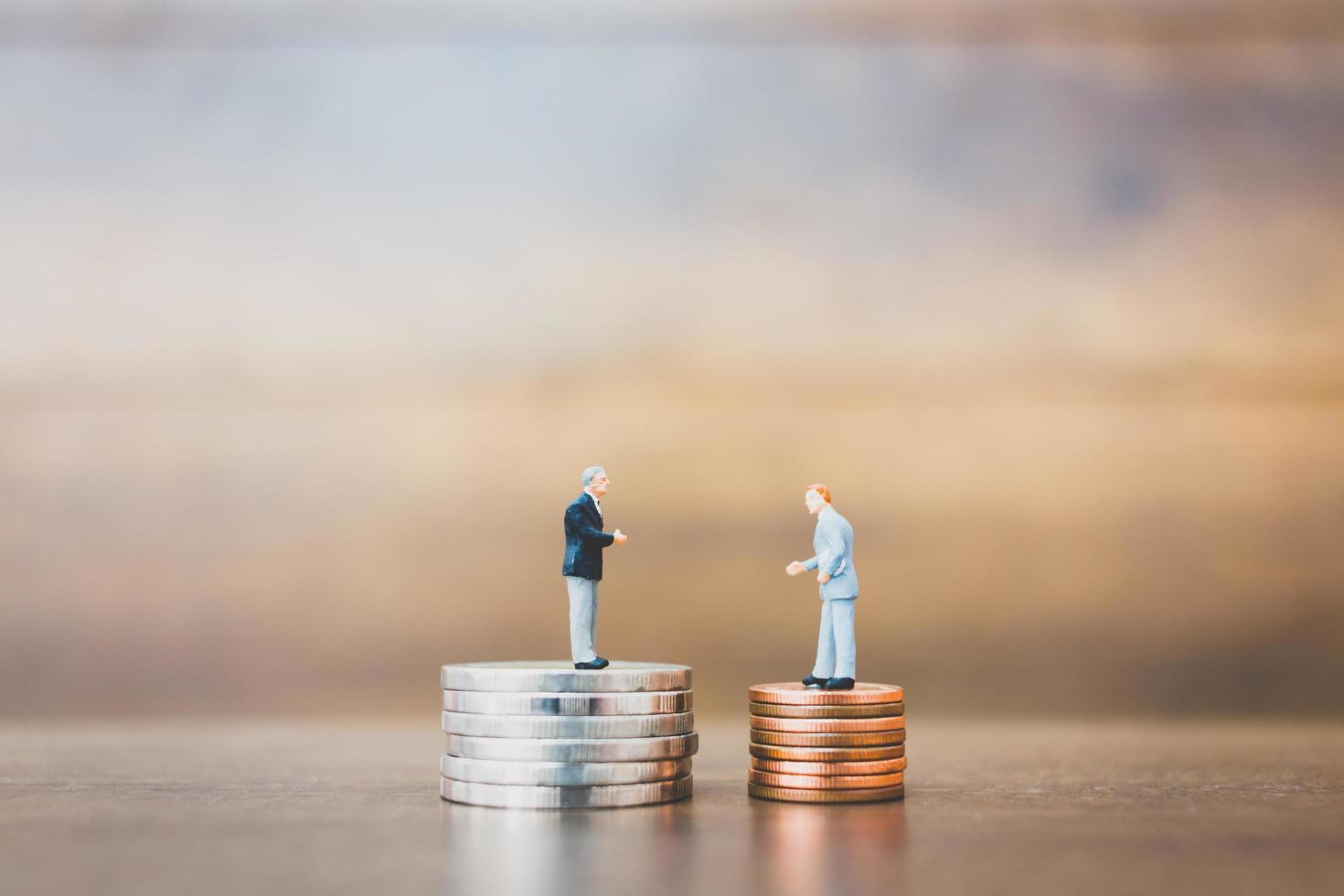 imprenditori in miniatura in piedi sui soldi con uno sfondo di legno foto