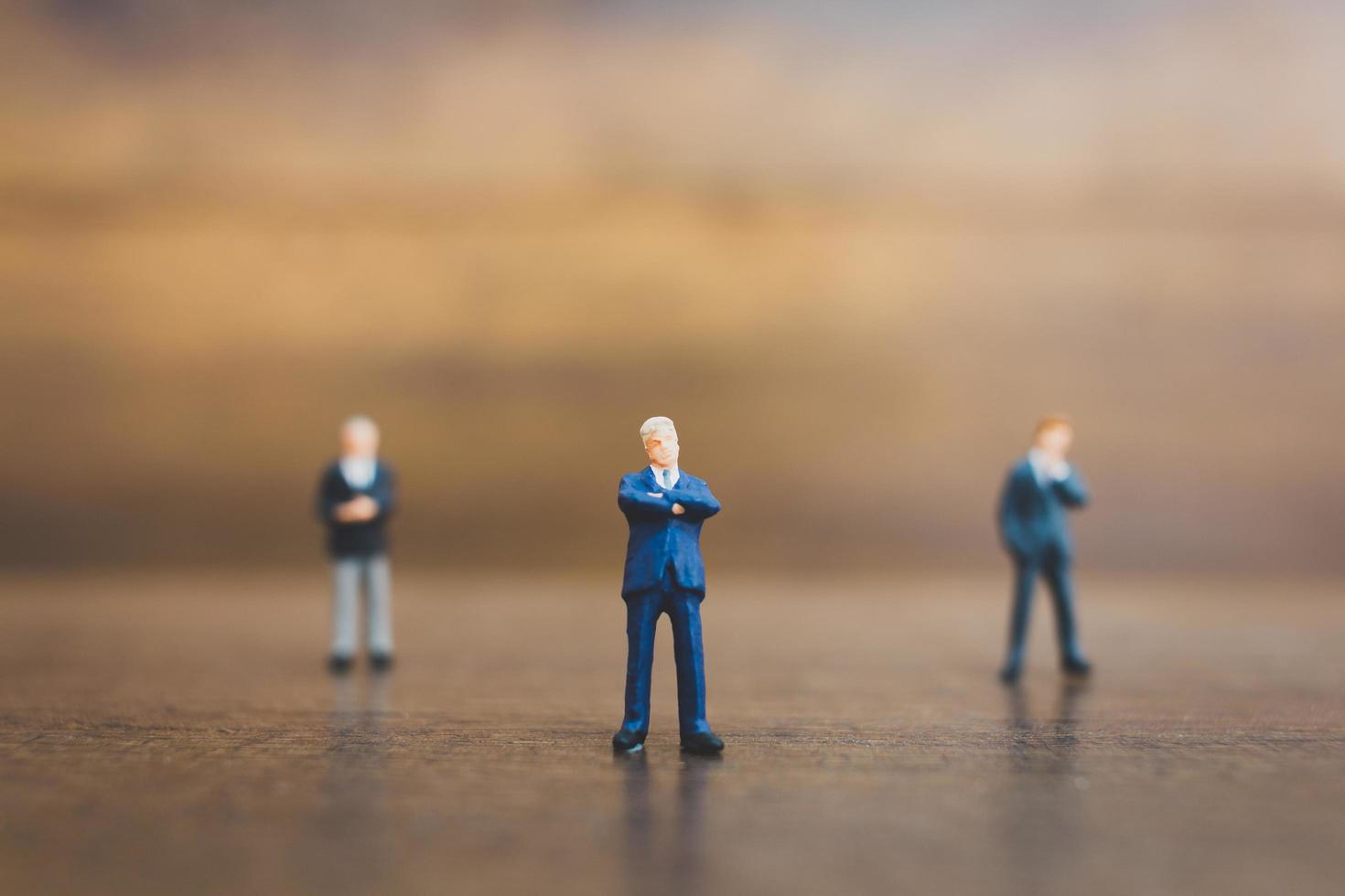 imprenditori in miniatura in piedi su uno sfondo di legno foto