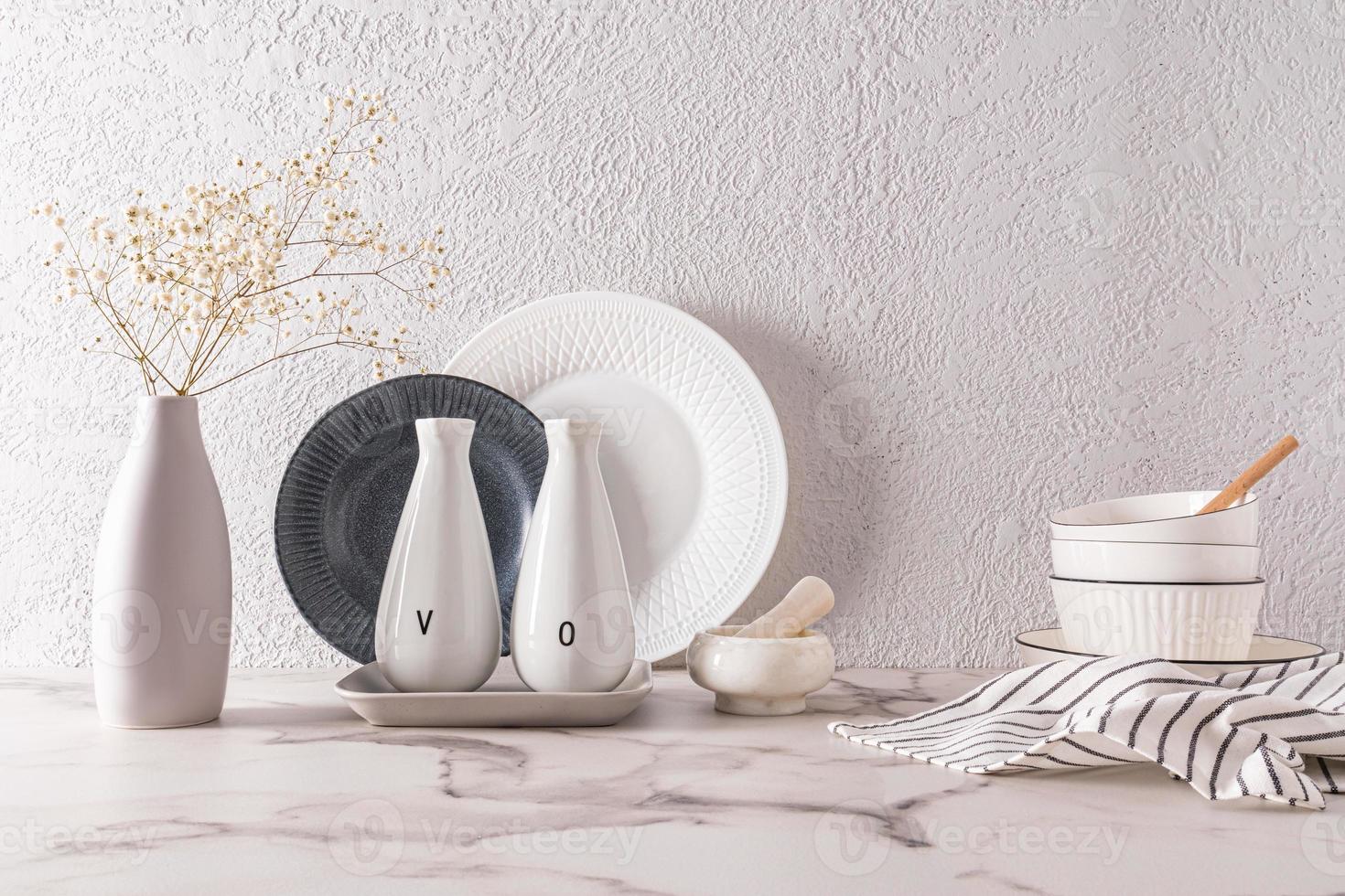 bianca elegante piatti contro il sfondo di un' grigio strutturato parete In piedi su un' marmo controsoffitto. il concetto di un' moderno cucina spazio. foto