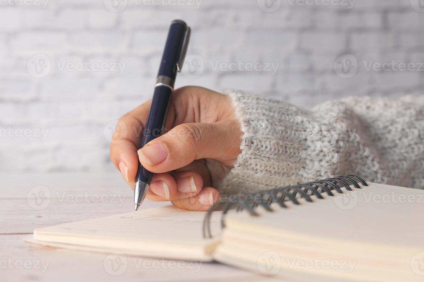 stretta di mano della donna che scrive sul blocco note foto